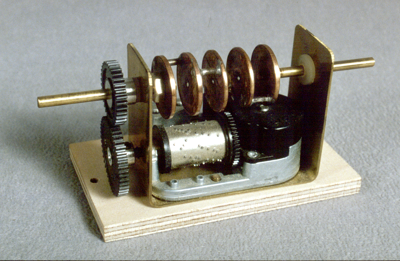 The controller prototype design is a stacked crankshaft made from pennies that has been silver soldered together and linked to a Sanyo music box movement with nylon gears used for slot cars.