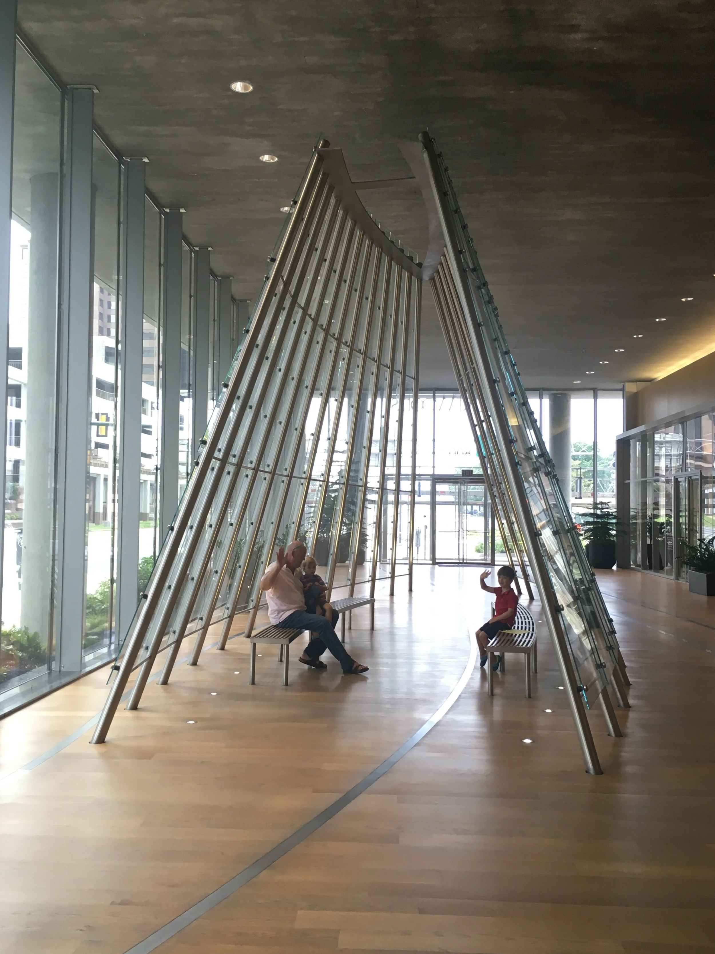 Hine family sitting and waving in Clear Passage, one of three elements of Gateway Trio (2015) in Clayco's Gateway Plaza building in Richmond, Virginia. (Photo: Laure Tillinghast Hine)