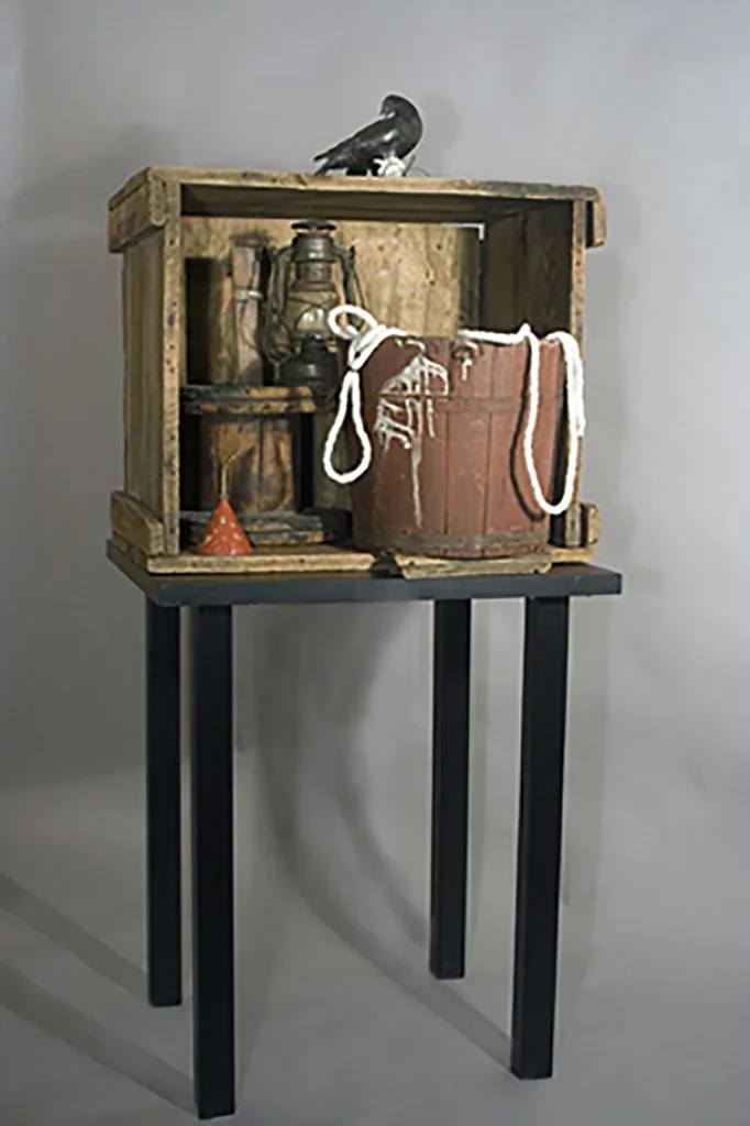 Sozodont. Assemblage of a deteriorated barrel, wood crate, spools and metal objects with a wounded bird of cast metal placed on top. 2010. 58"H (including table) x 26" x 26" x 22".
