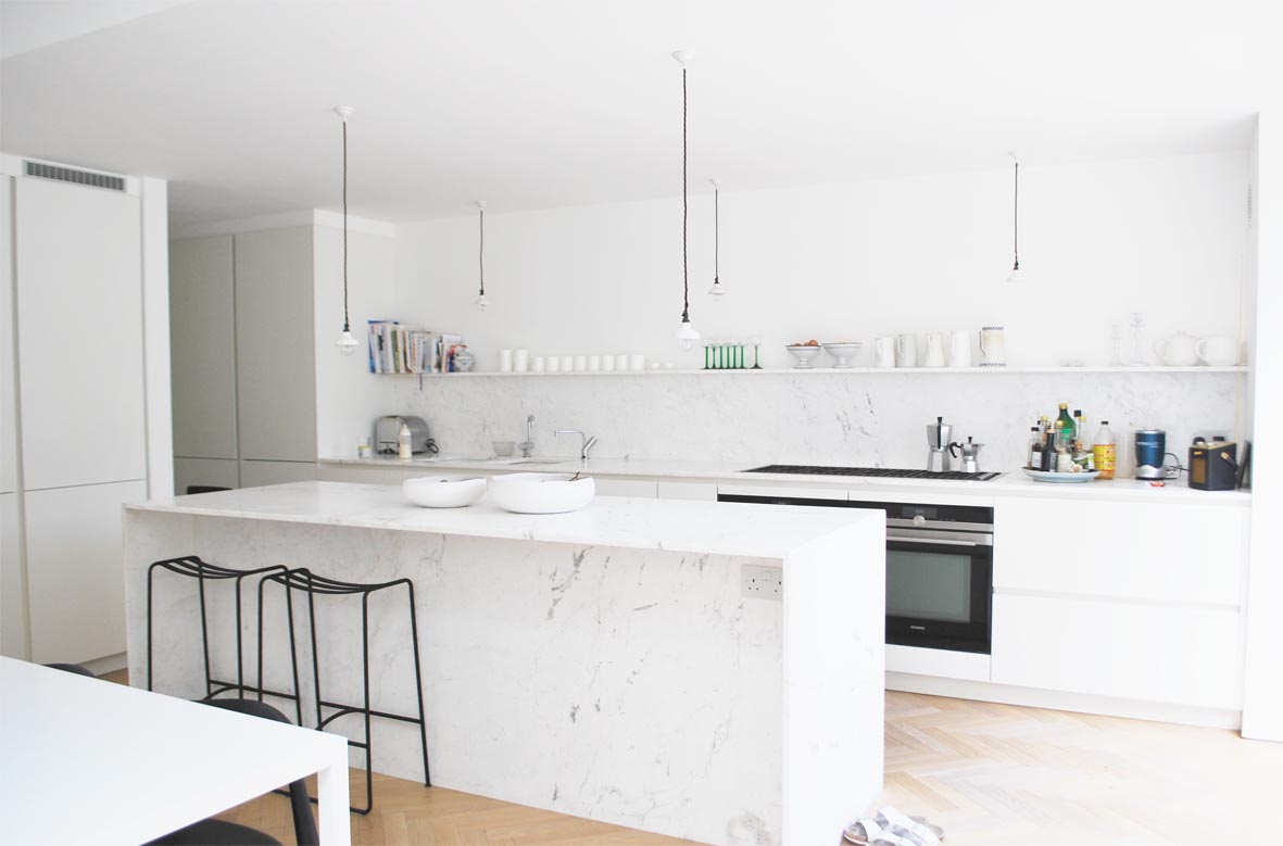 The pale marble encases three sides of the kitchen island.