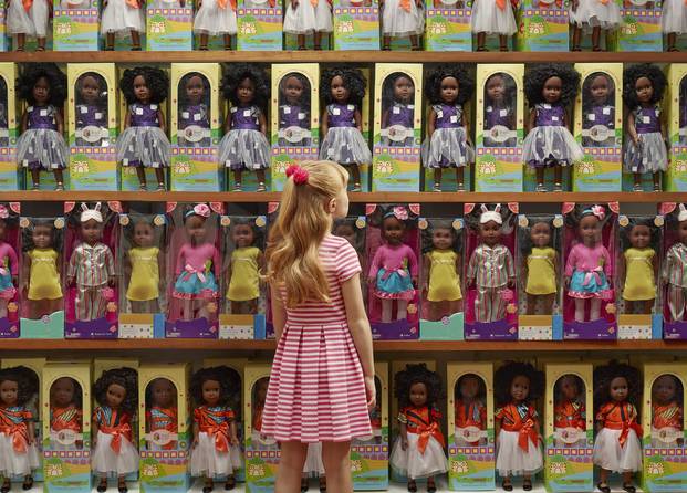 A young white girl looking up at shelves upon shelves of black dolls. Source: Chris Buck/O, the Oprah Magazine