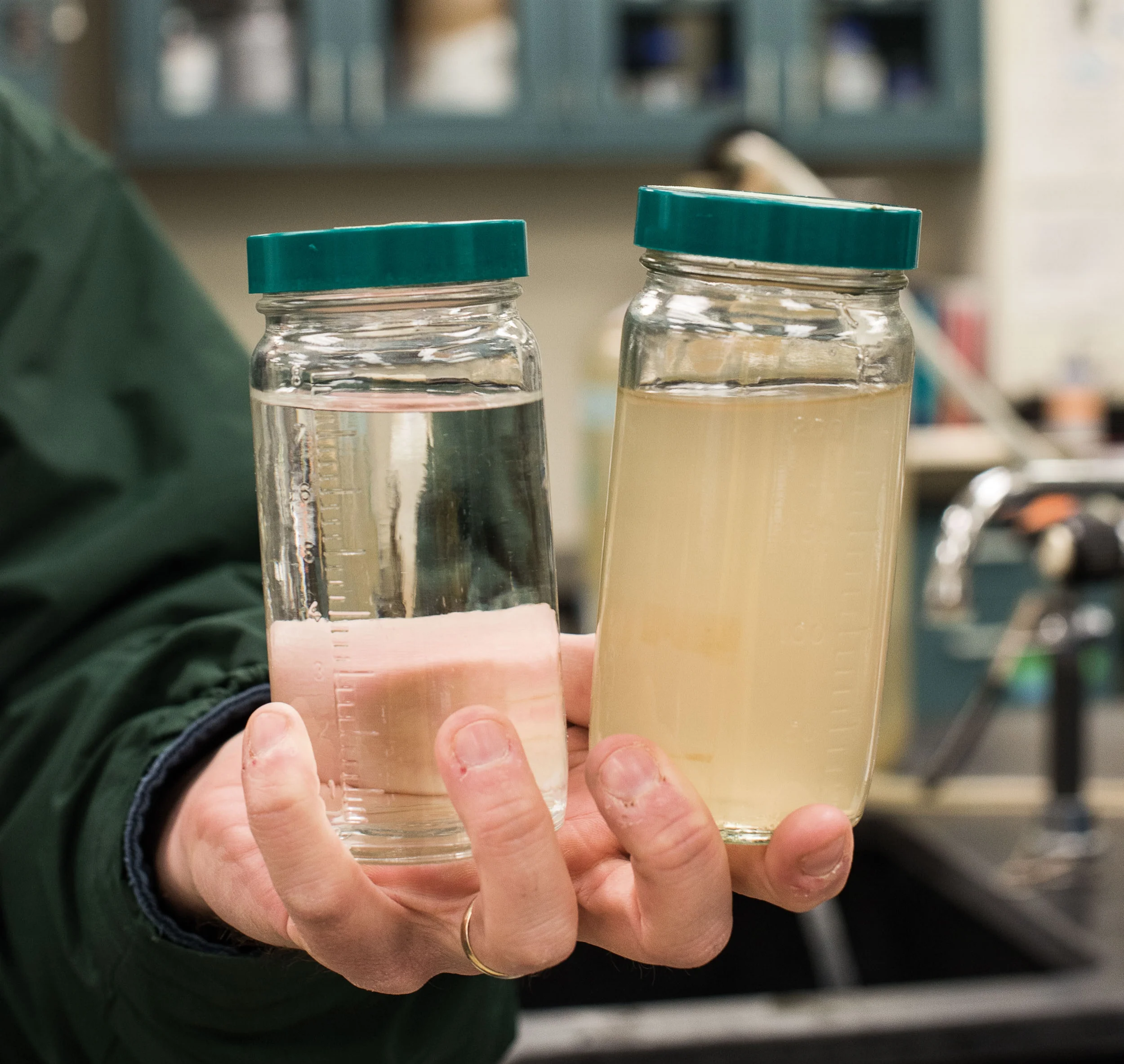 Jeff Swertfeger, who monitors water quality at Greater Cincinnati Water Works, holds water from the Ohio River. Finished water (left) and raw (right).