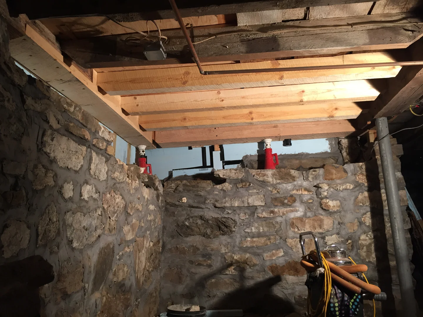 The stone foundation was dismantled and the rotten sills were removed and scarfed to receive new material. New locally-sourced and rot-resistant white oak sills were scarfed to the structurally-sound remaining portions. The three damaged joists were replicated and replaced. The masons can now rebuild the walls beneath the sills.