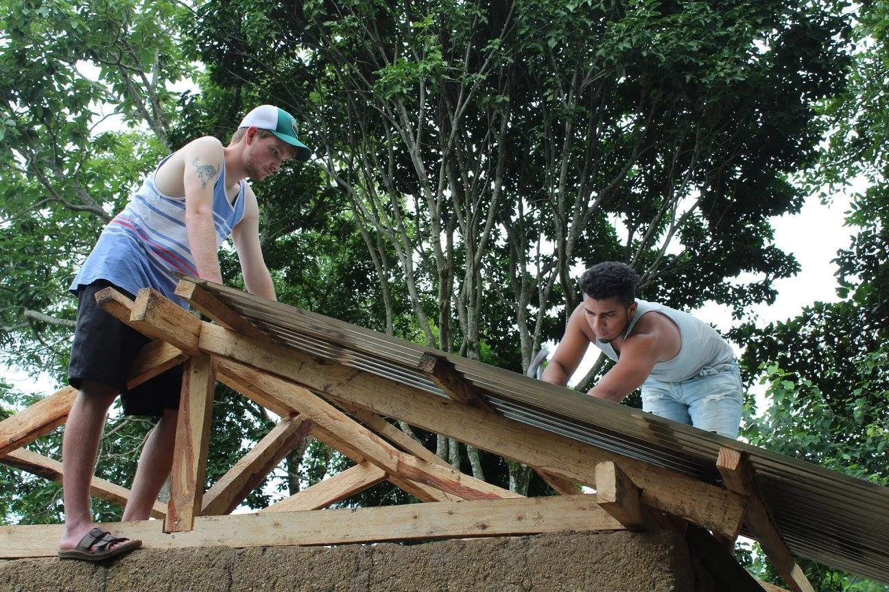 Two volunteers, one from one country and the other from another country, working side-by-side showing a Mercy familiy the love of Jesus by replacing the roof.