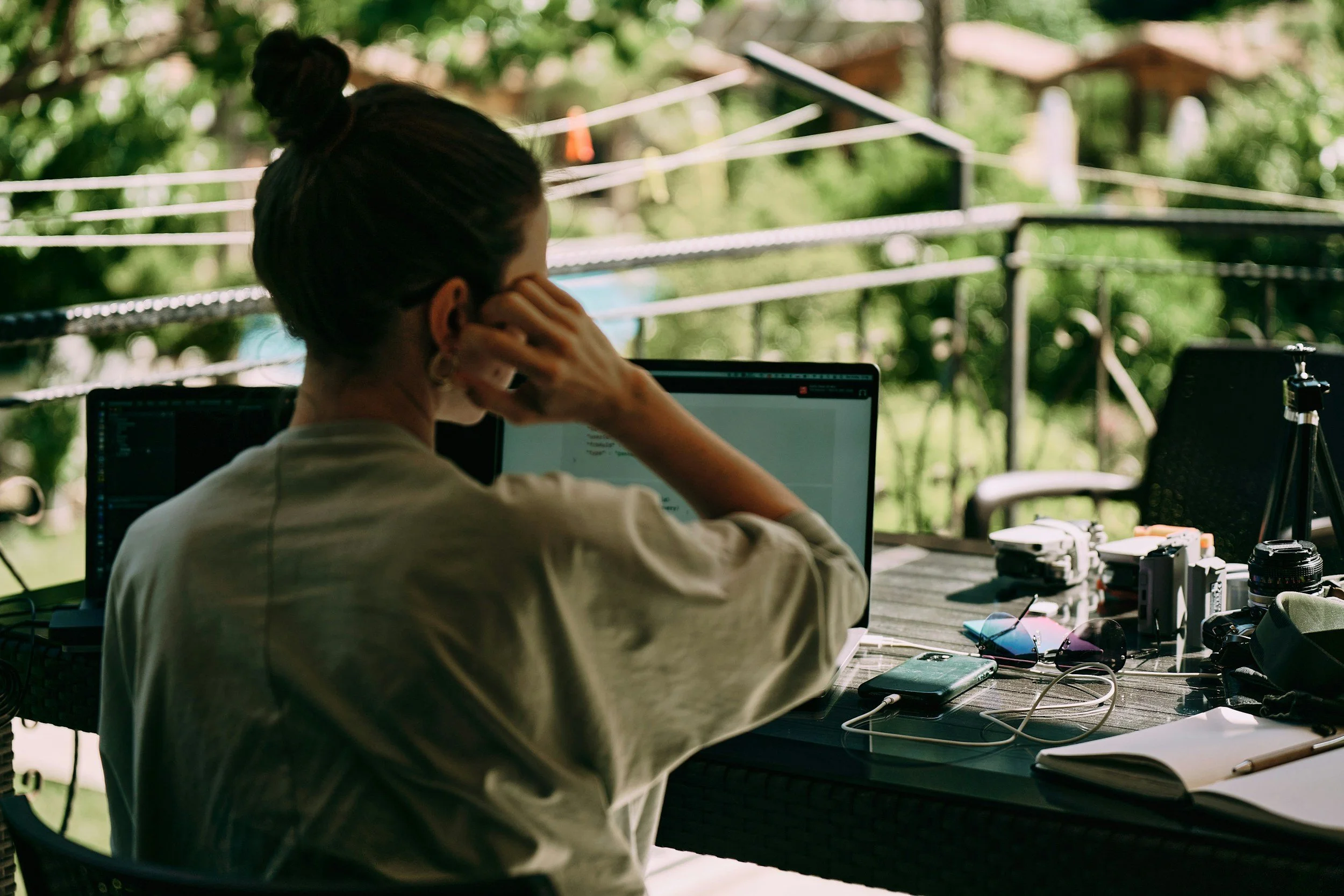 Growth Operator Digital Nomad in Bali in front of a mac book sitting at a table with phones and cameras spread out