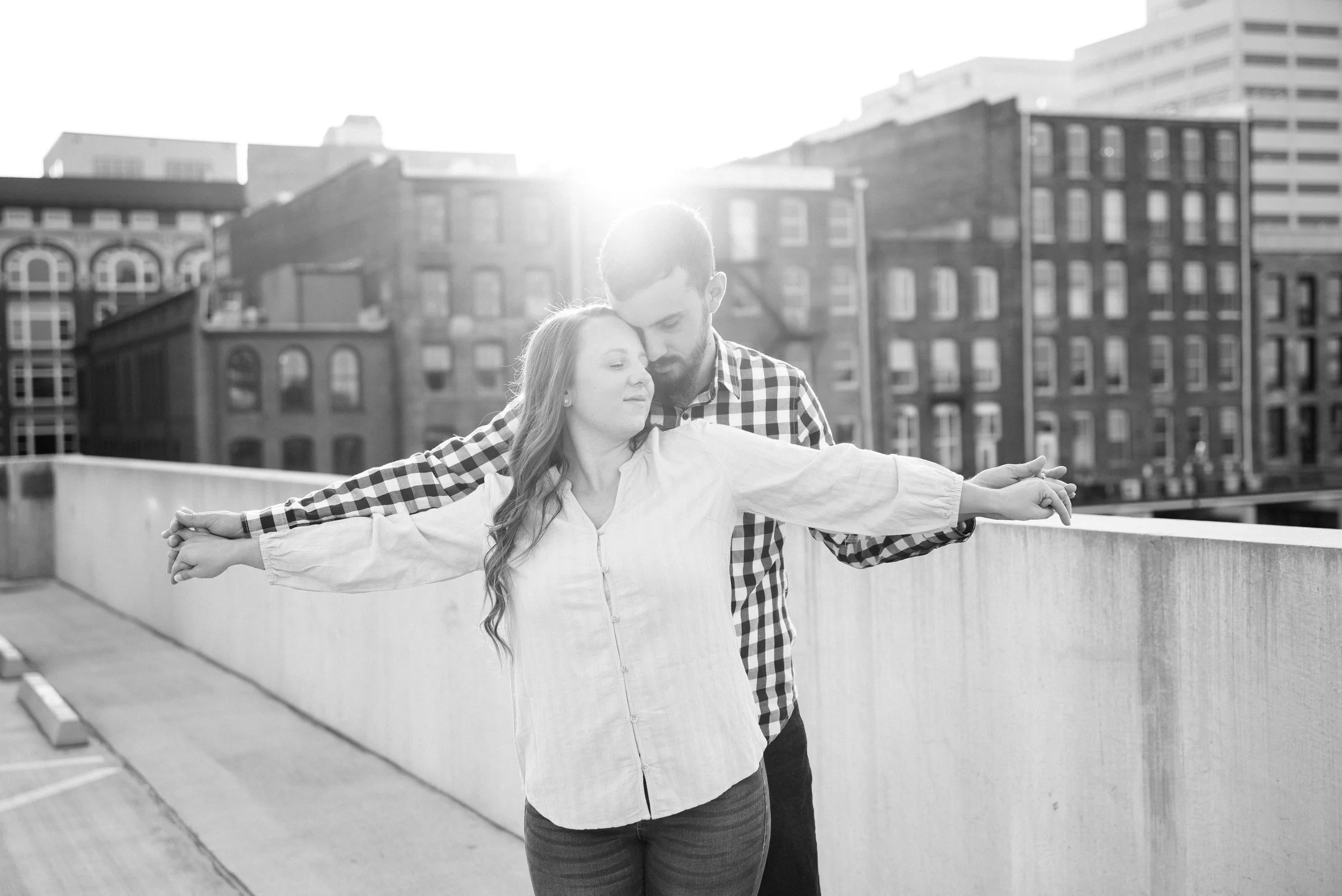 Couple embracing during a rooftop portrait session overlooking downtown Knoxville, Tennessee