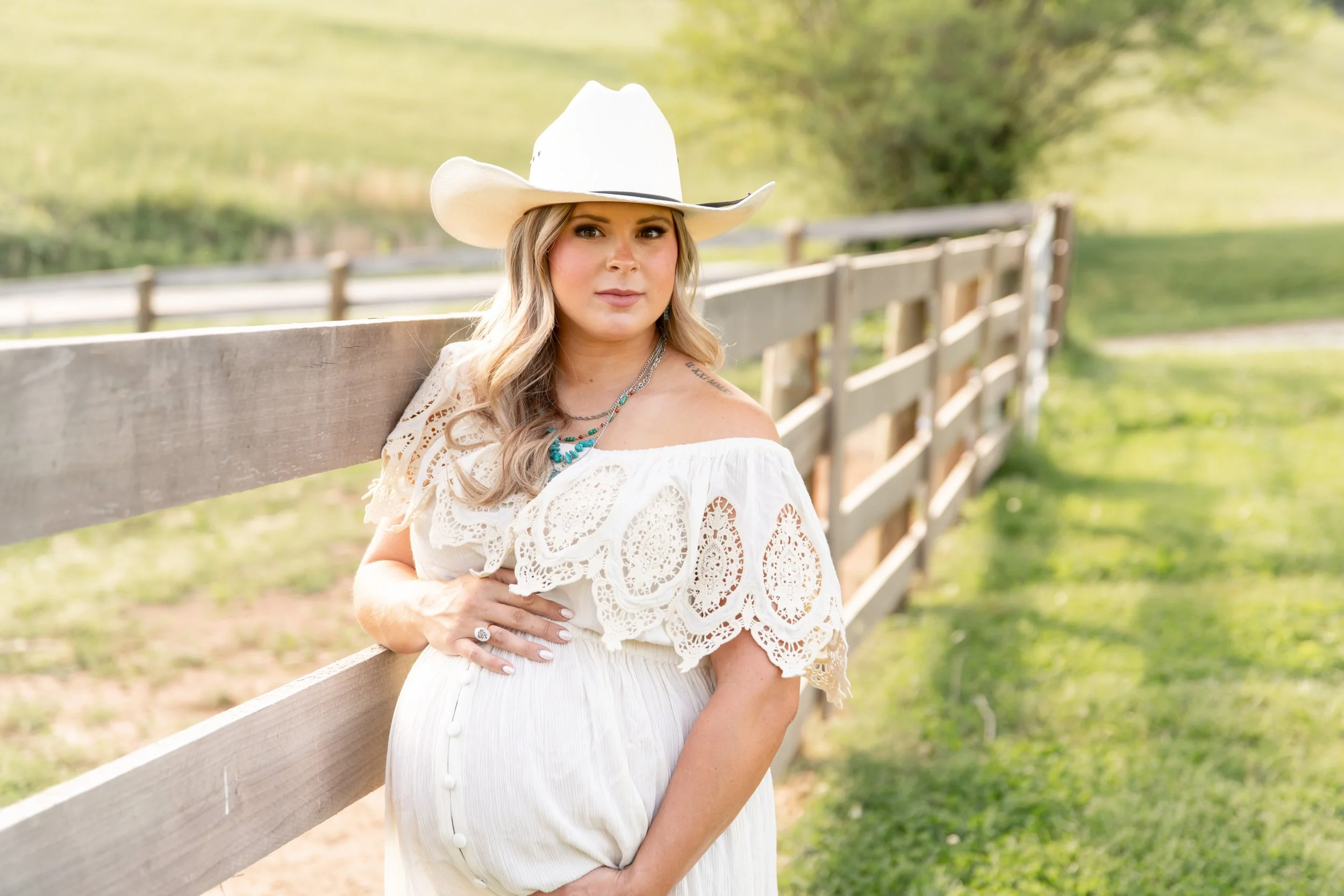 Expectant mother in a white cowboy hat during an outdoor maternity photography session in Knoxville, Tennessee
