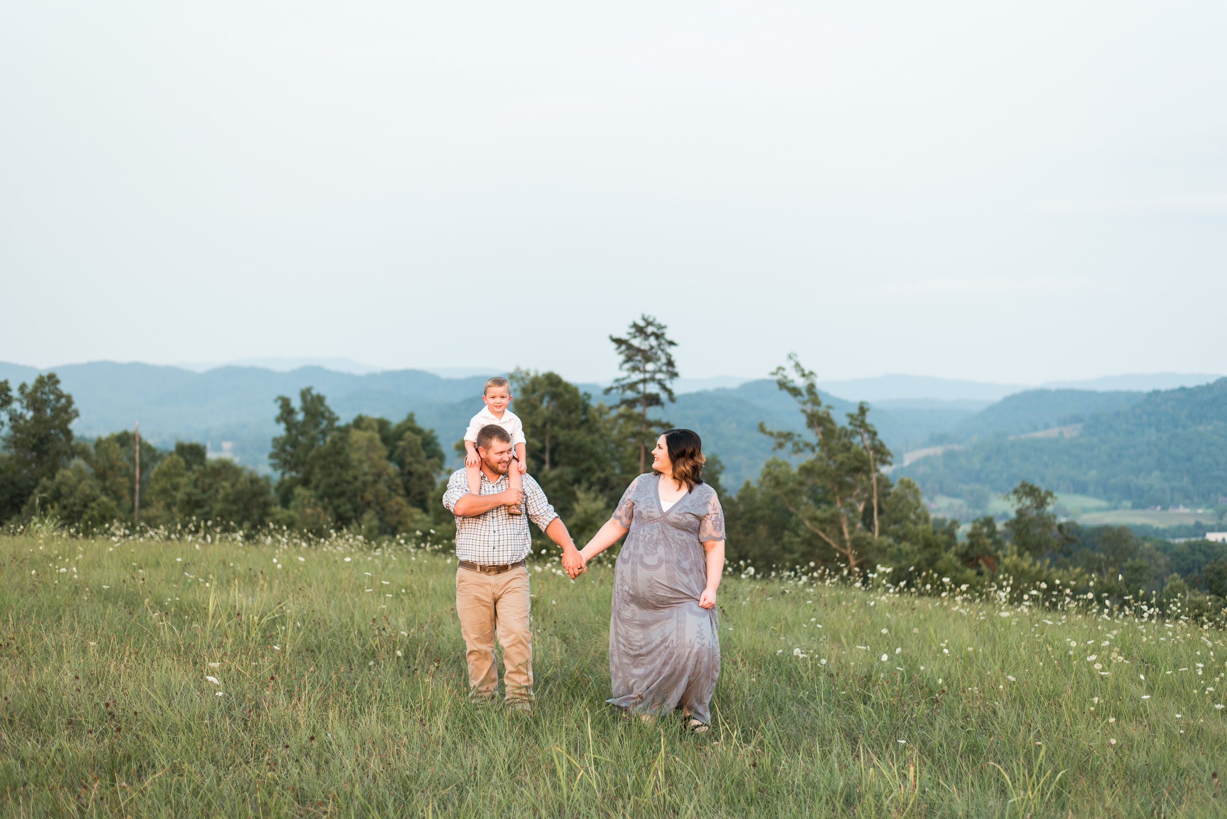 Expectant mother walking with her husband and son during a summer family maternity session in Maynardville, Tennessee