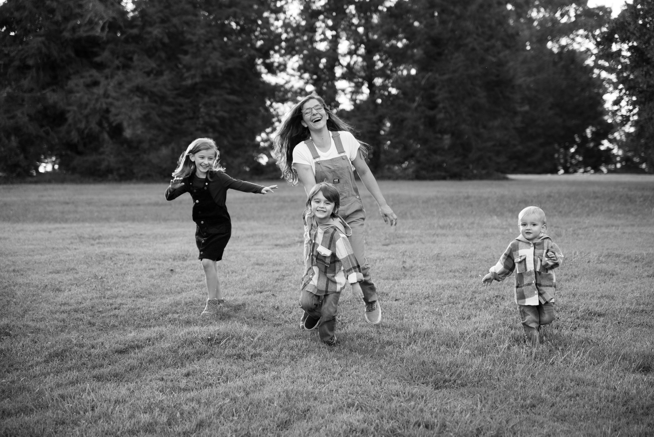 Mom and three children running and laughing during a family session at Knoxville Botanical Garden and Arboretum in Knoxville, Tennessee