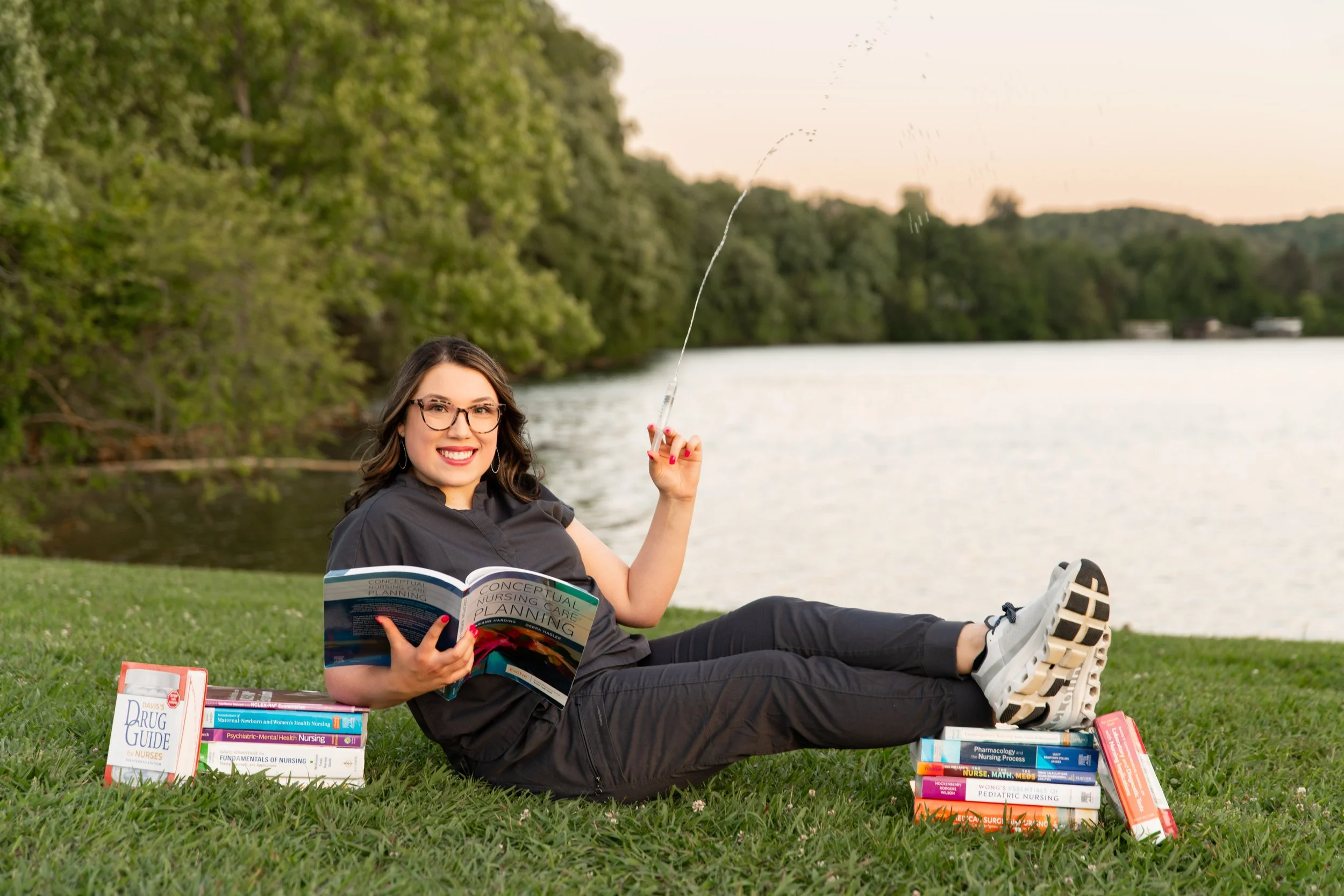 Nursing school graduate celebrating with books during a senior portrait session at Melton Hill Park in East Tennessee