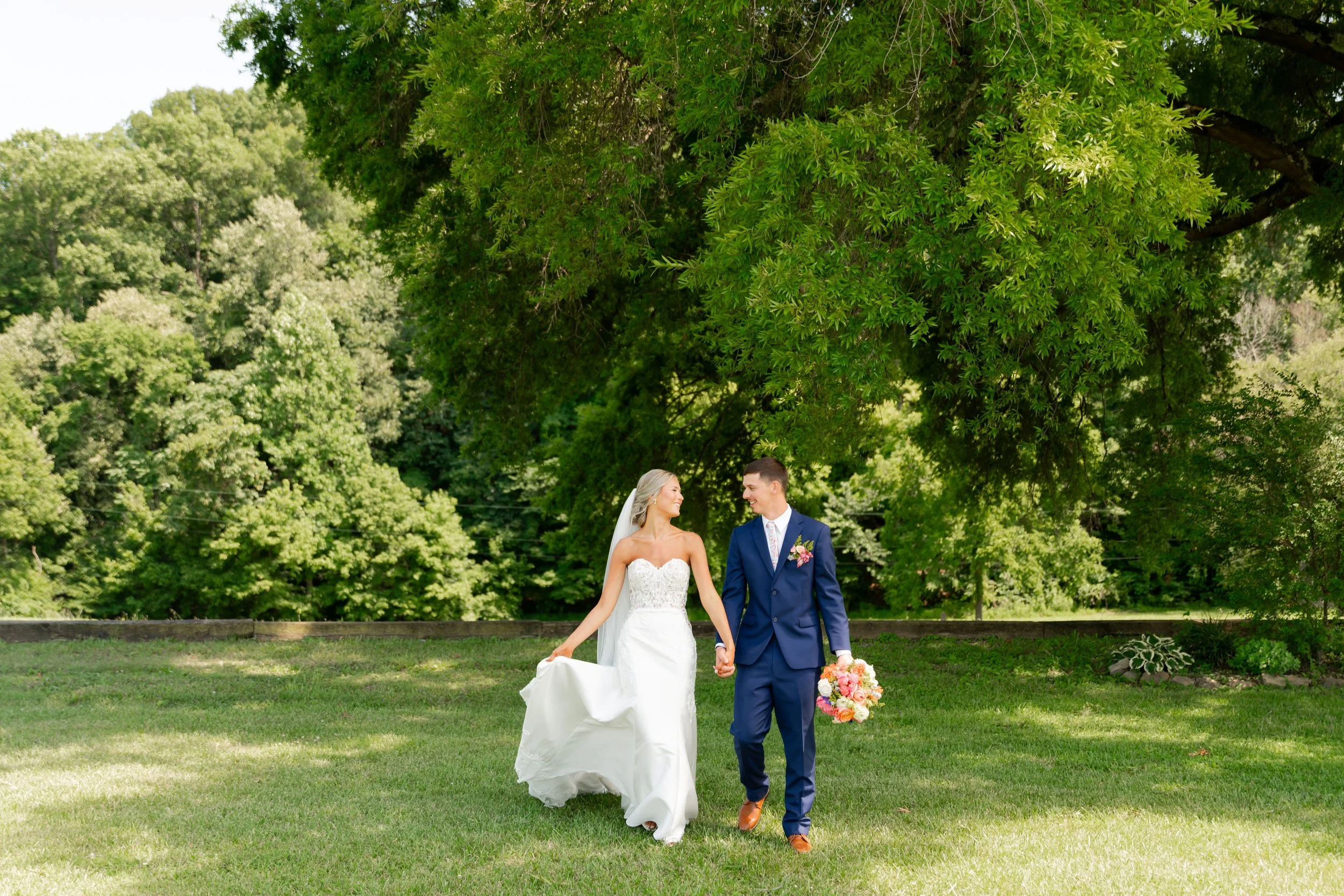 Braelyn and Skyler walking together during their summer wedding at The Farm at Bentley Fields in Newport, Tennessee