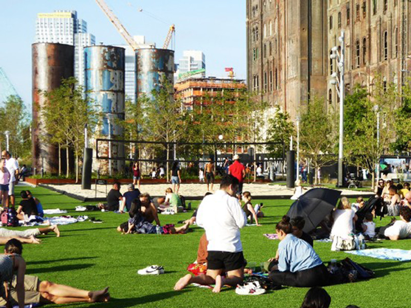 Lawn area with heritage tanks &amp; Domino Sugar factory building beyond