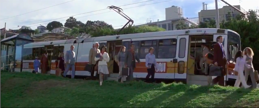People disembark a Muni bus onto a lawn.