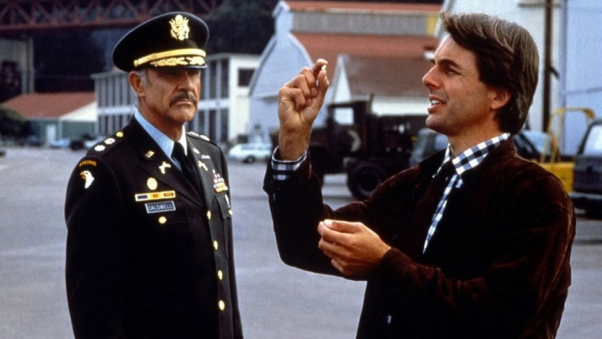 A man holds up a bullet to examine as a military commander in uniform looks on.