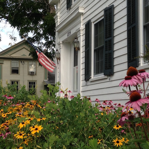 Cone flowers and black-eyed Susan enliven the front of this greek revival cottage in Essex, NY