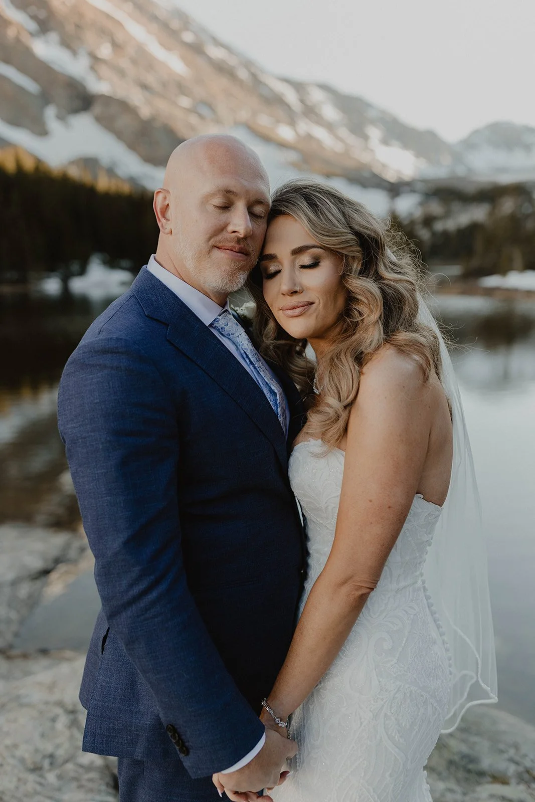 A bride and groom hug each other on their Breckenridge mountain elopement in front of an alpine lake