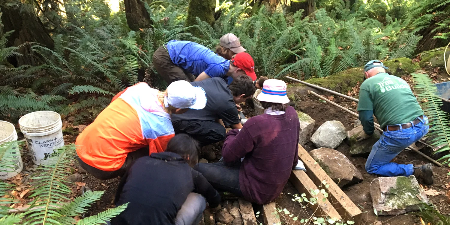NOLS students and instructor helping build slot drains.