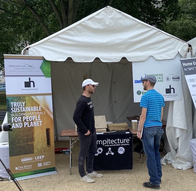   Tommy Gibbons (left), Hempitecture's co-founder and chief innovation officer, discusses the company’s hemp-based insulation with an attendee of the 2023 Innovative Housing Showcase on the National Mall in Washington, D.C., June 9, 2023.    Photo by