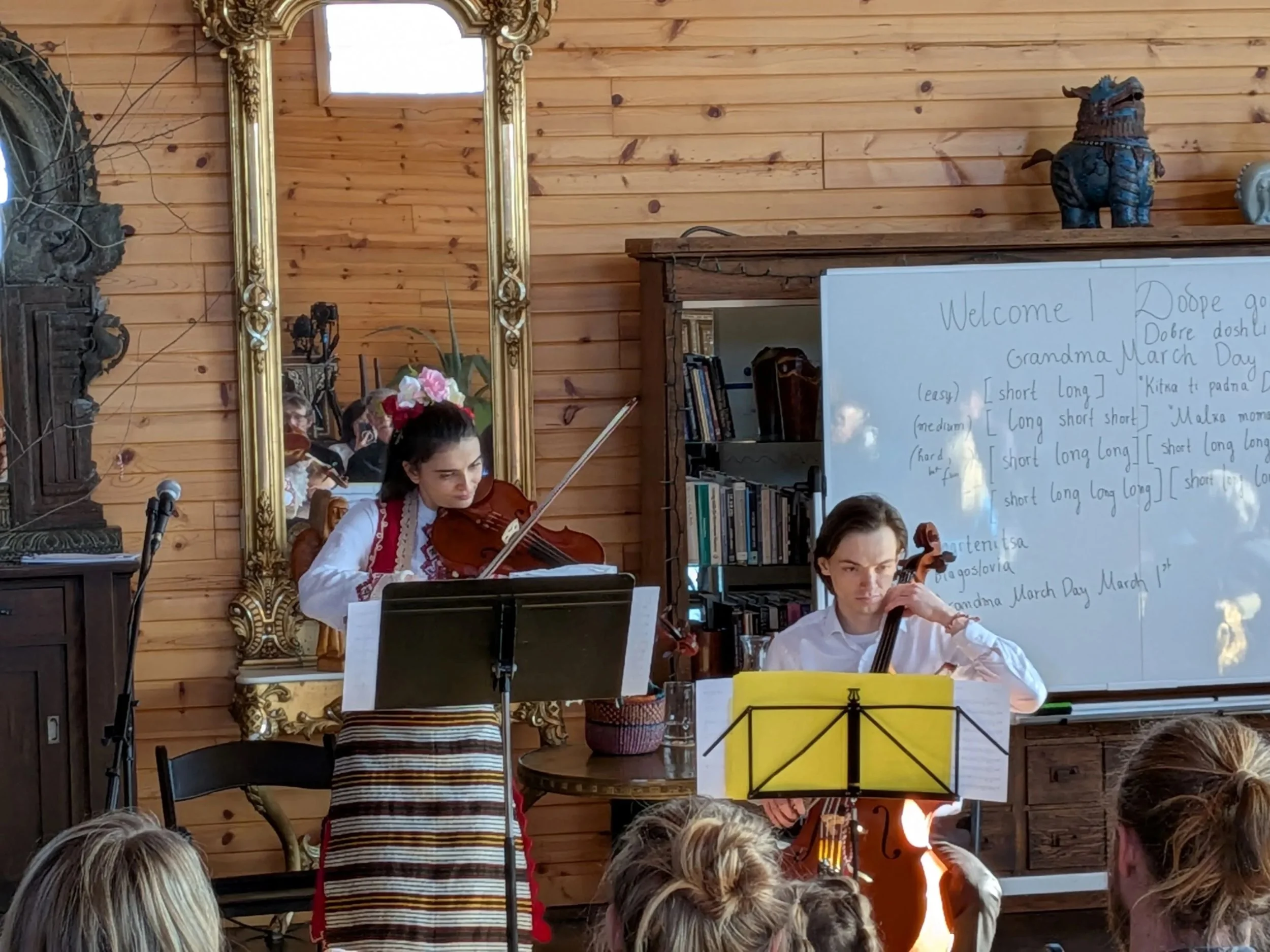 Two people playing instruments in front of a large mirror
