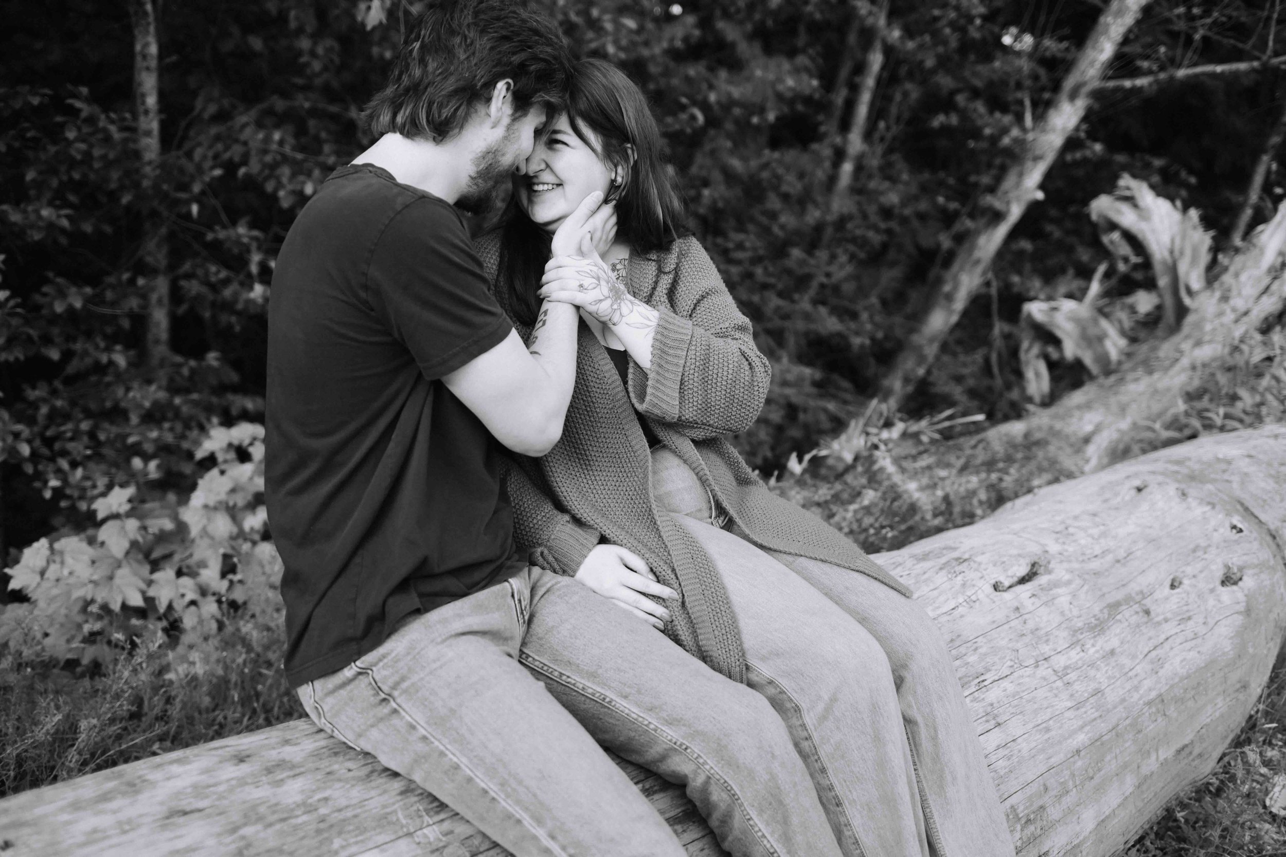 Vancouver couple sits on log and cuddles for a cozy photo