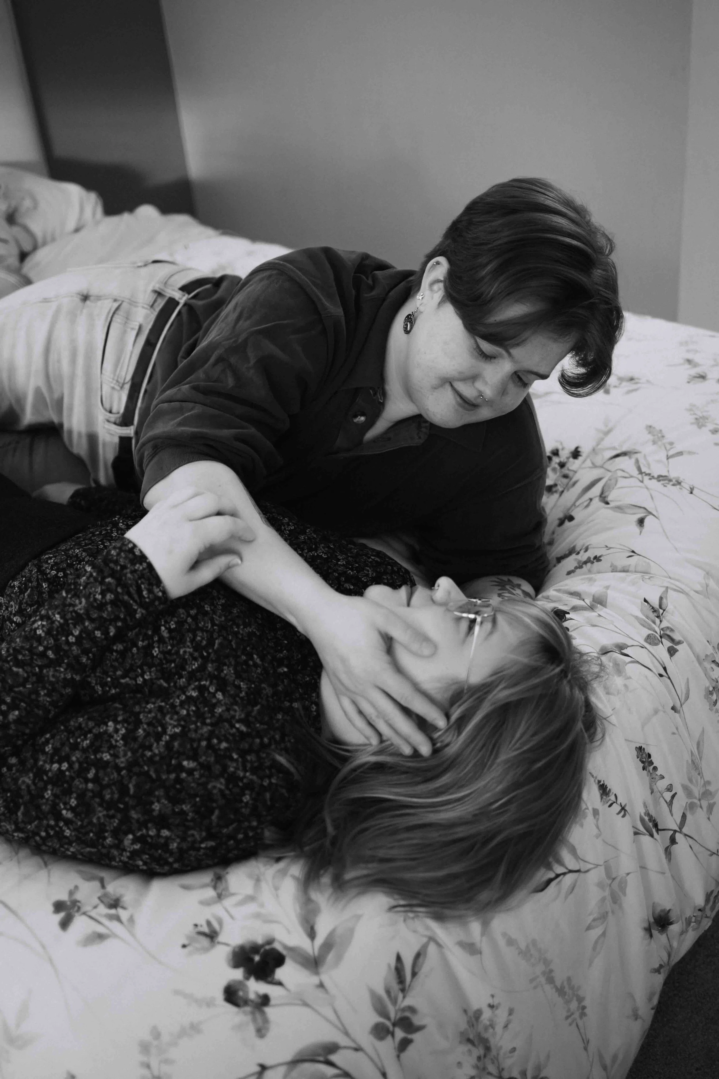 Vancouver lesbian couple lay in bed and tenderly caress each other