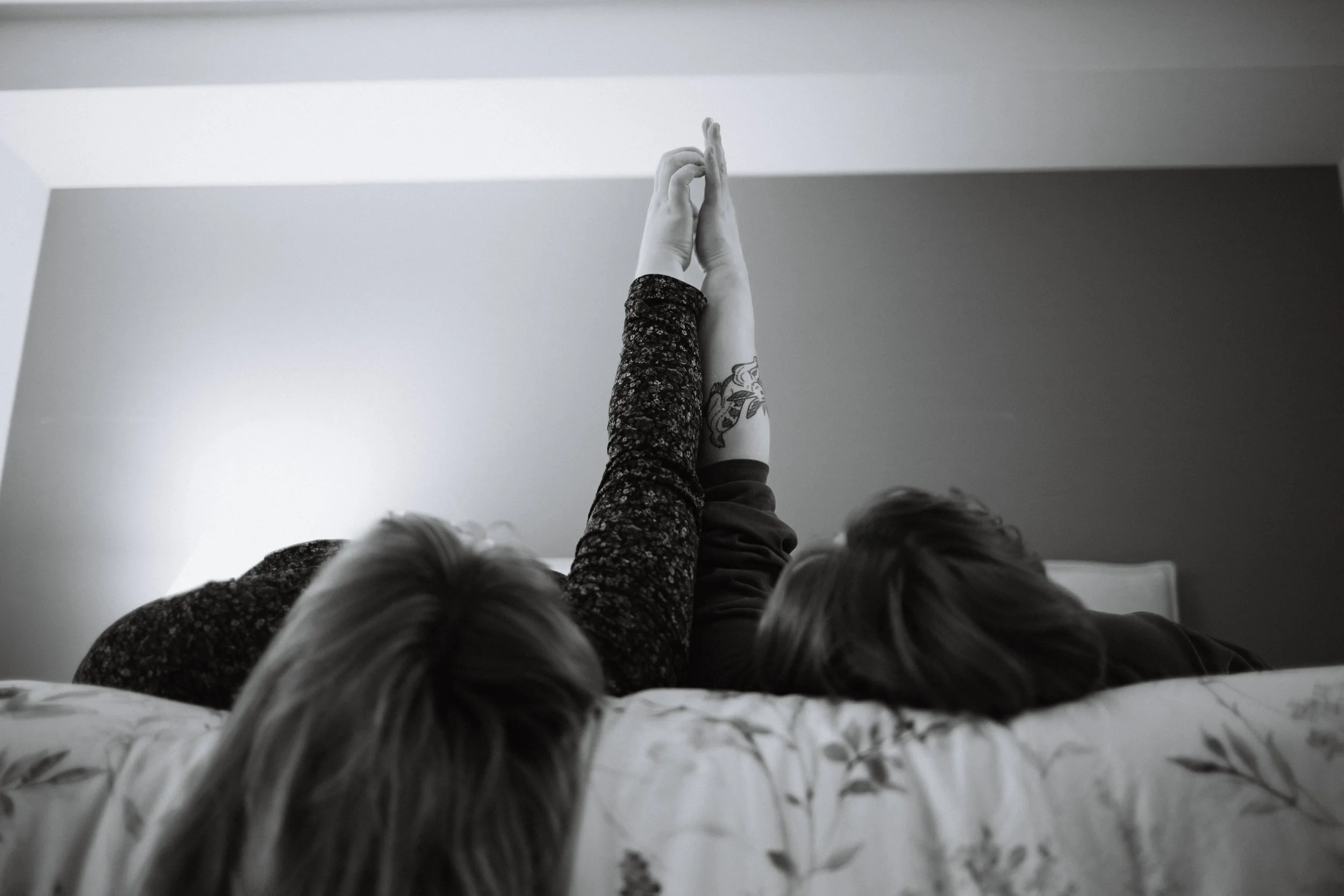 Vancouver couple traces hands while cuddling in bed.