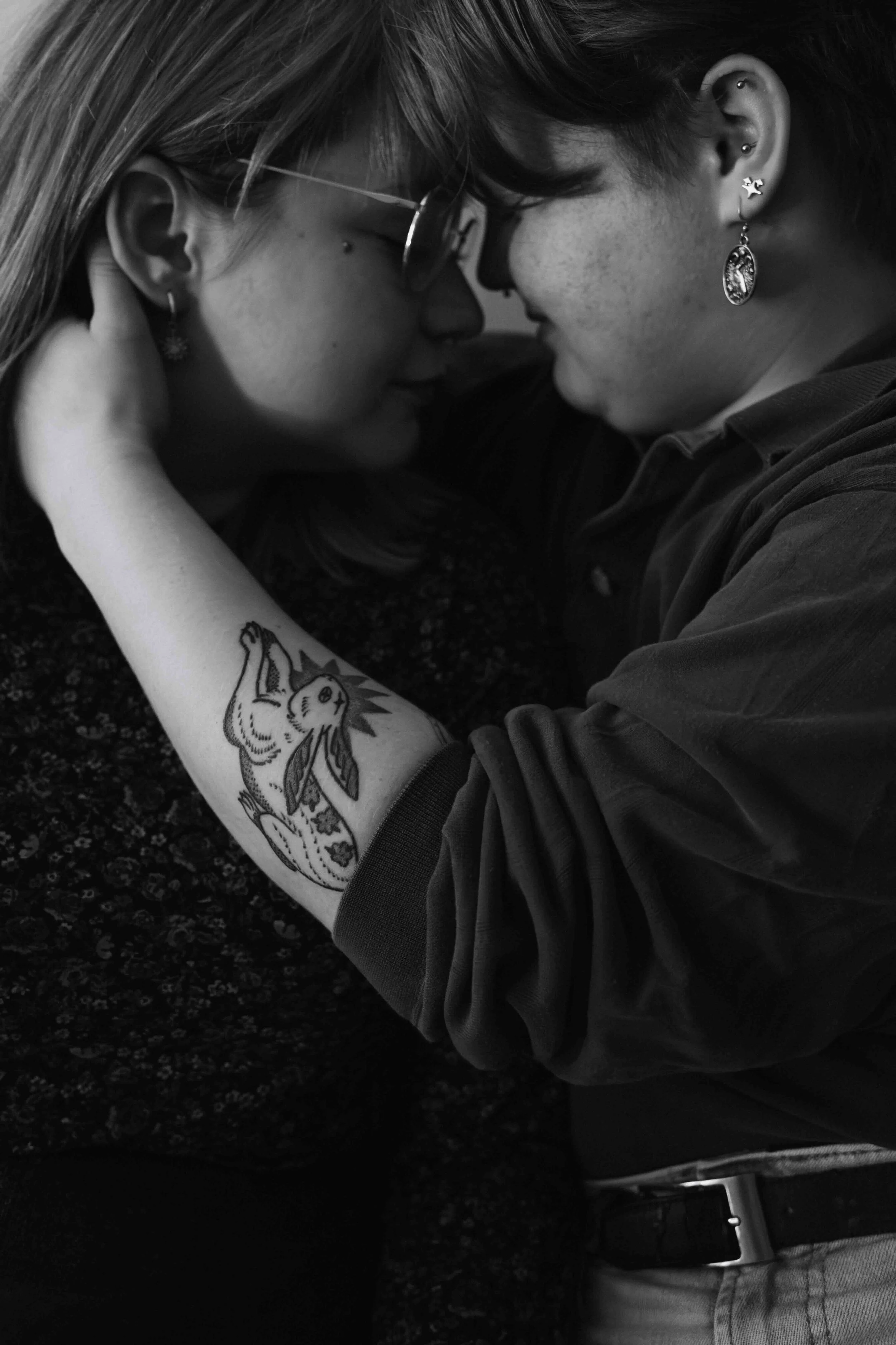 Tattooed Vancouver couple snuggles as one caressess their girlfriend's hair