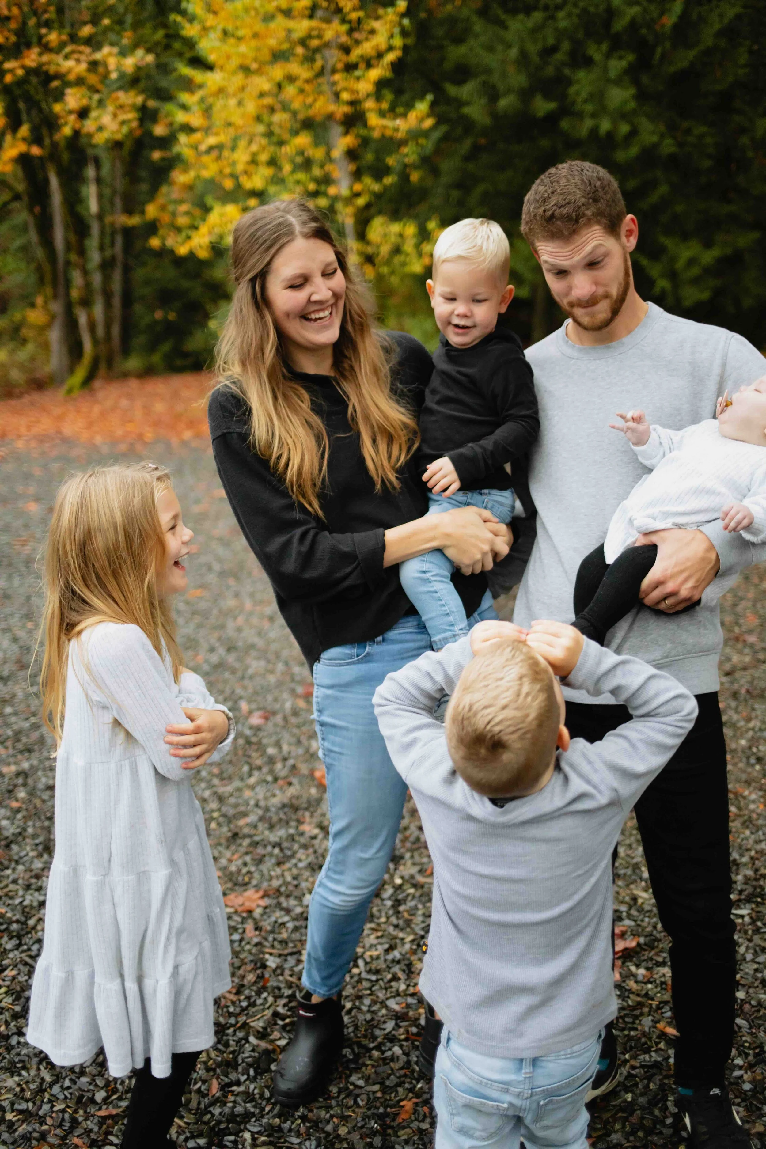 Young Vancouver family laugh and make silly face while playing in autumn background