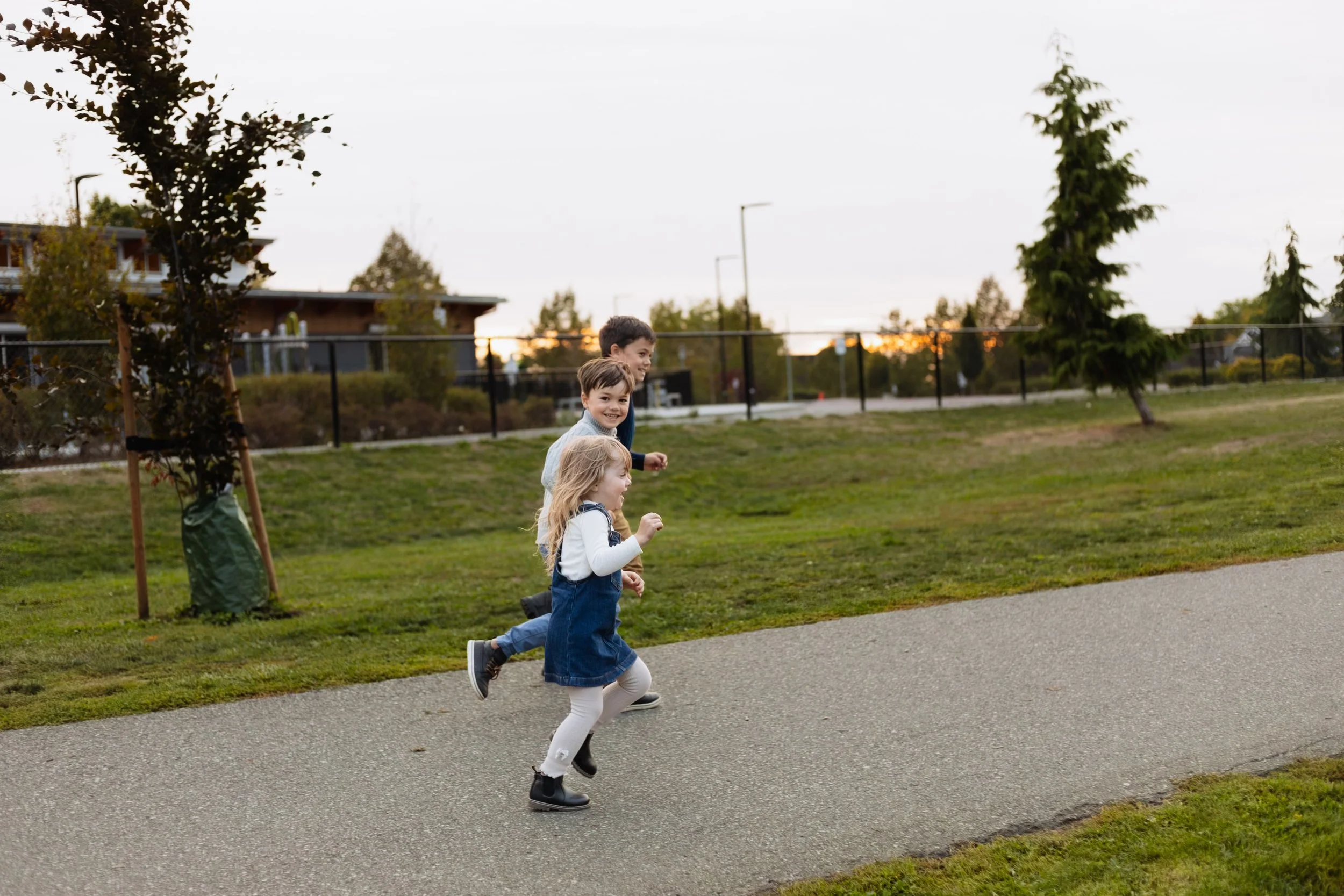 Young Vancouver kids run along path playing in their neighbourhood as sun sets