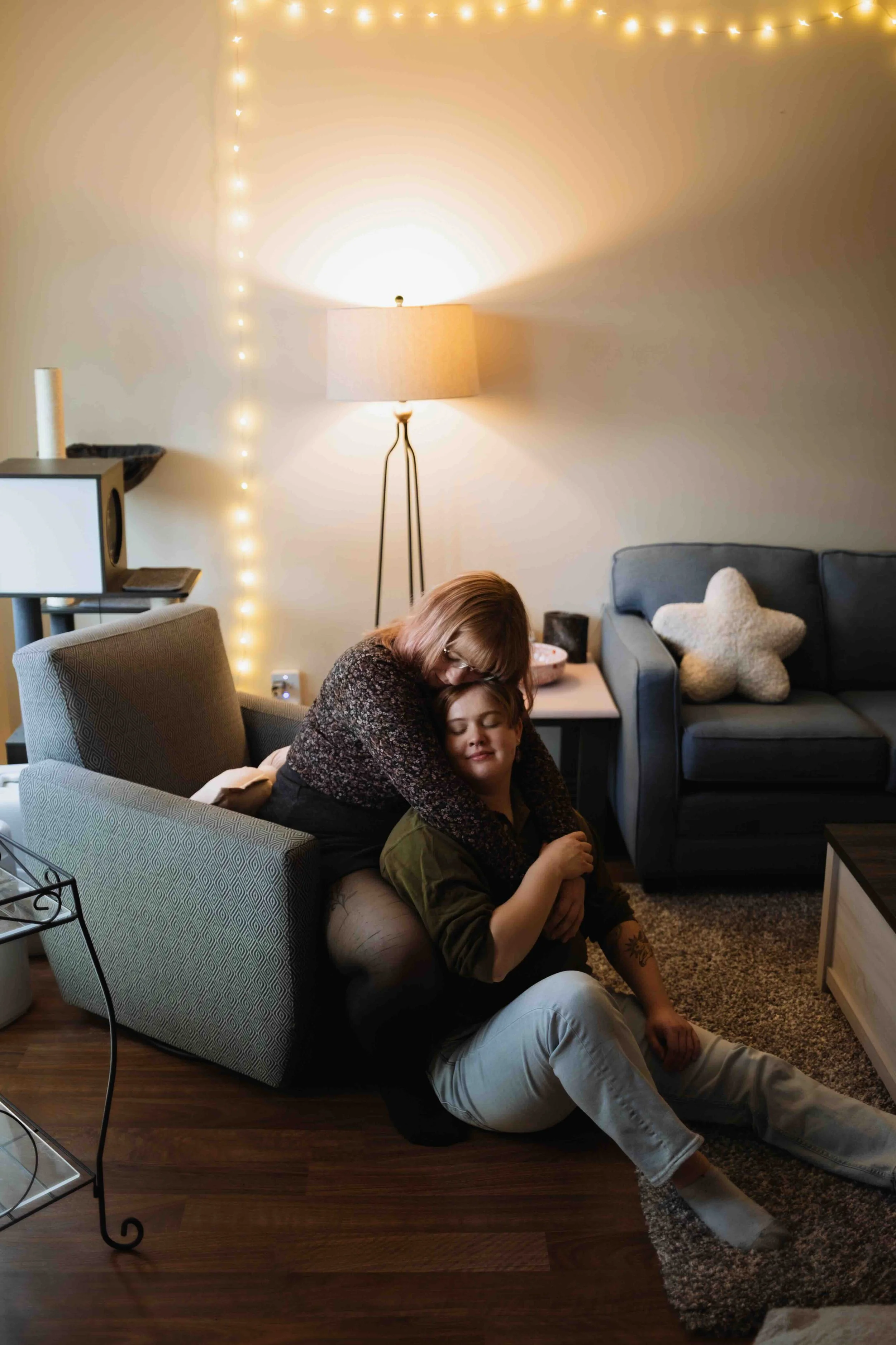 Queer Vancouver couple gentle and soft in home embrace sitting on chair