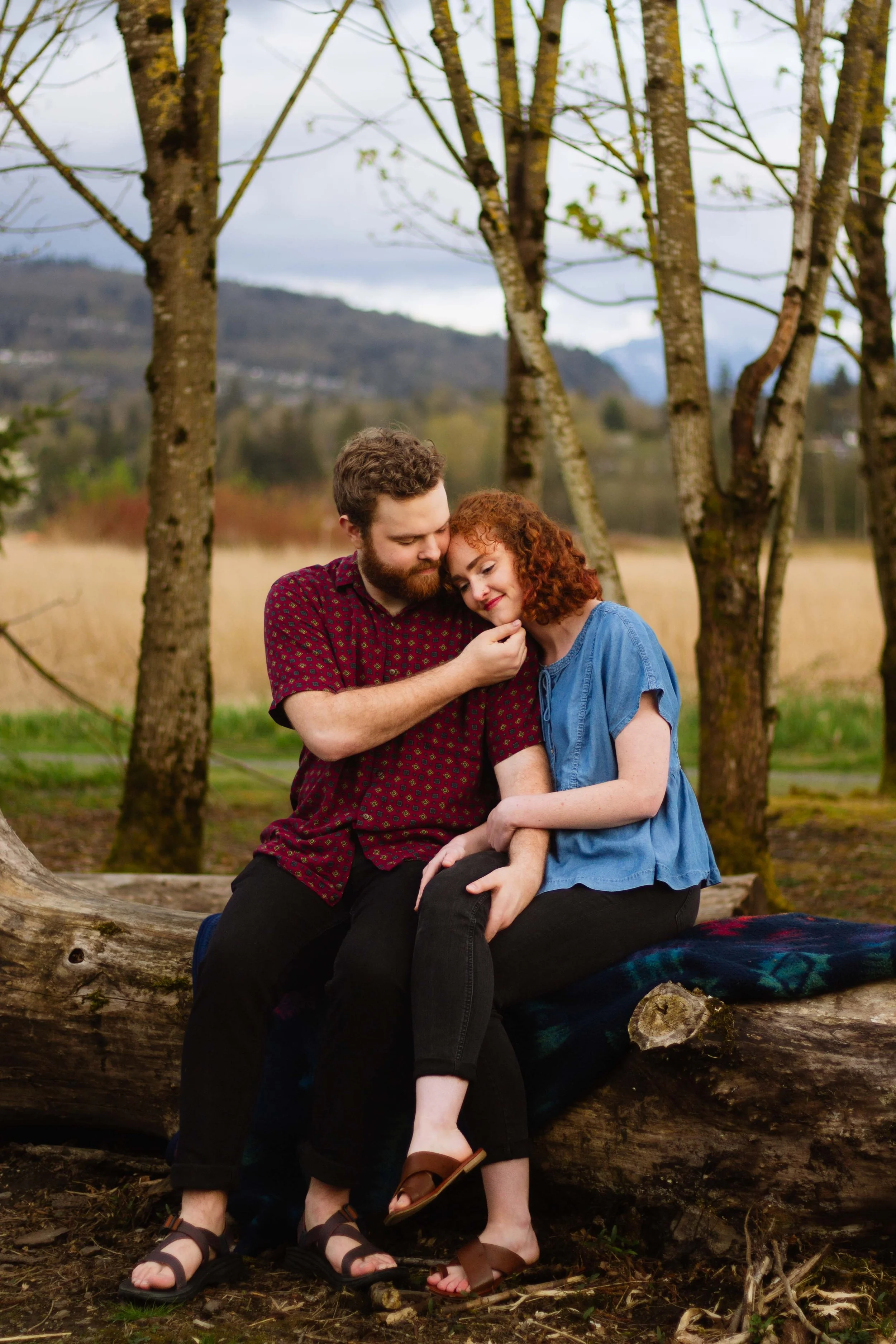 Abbotsford couple cuddles on log at Willband Creek Park