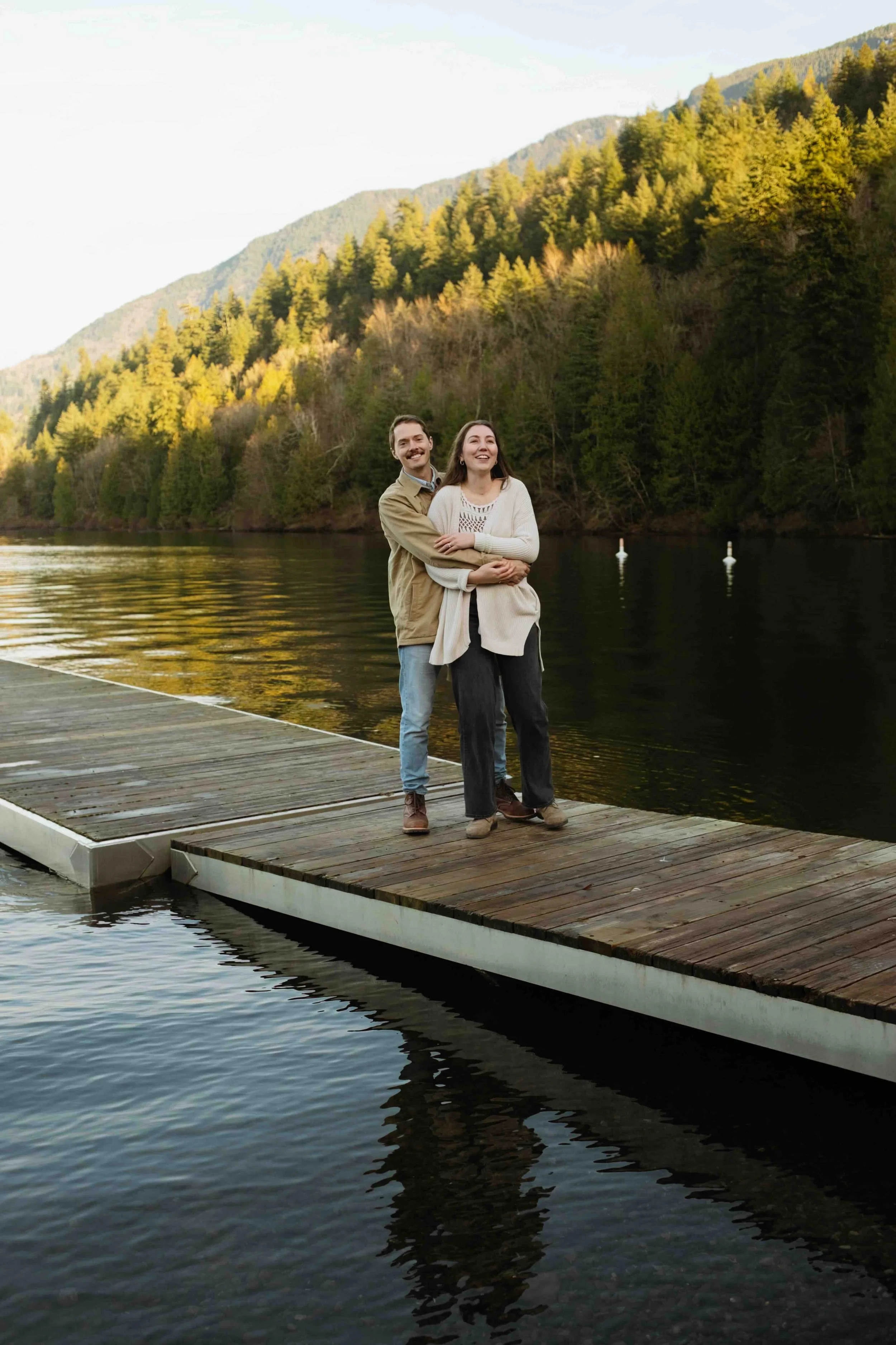 Reflection in a lake of a Vancouver couple cuddling on a dock