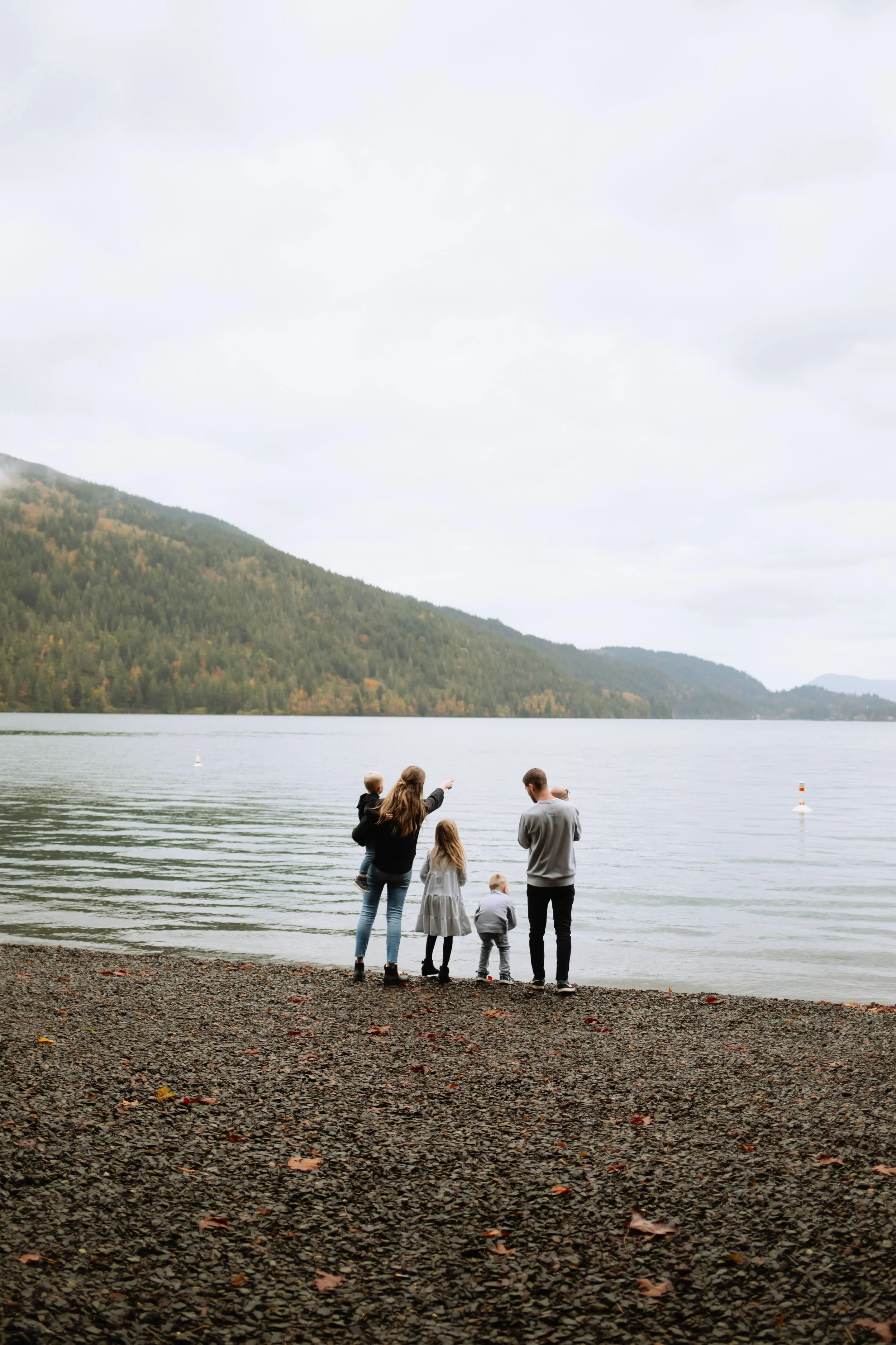 Young Vancouver family silhouetted against mountain Cultus lake