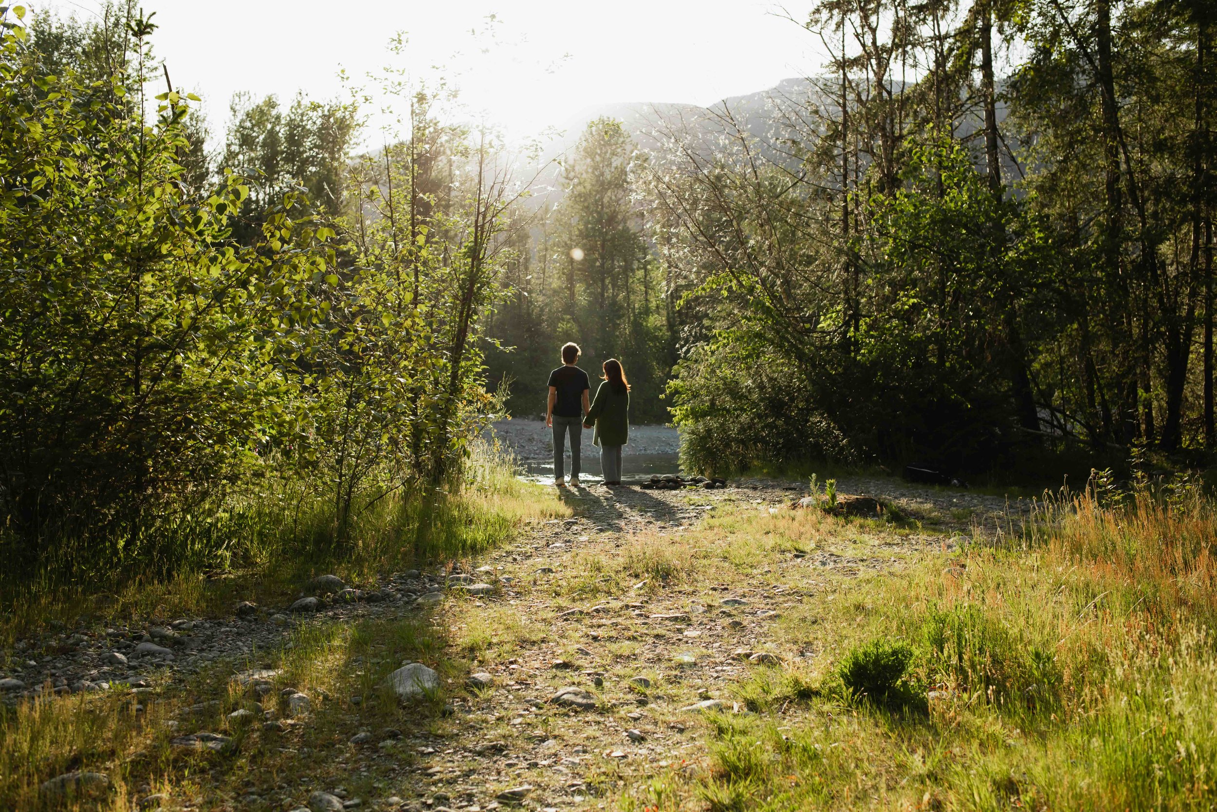 Vancouver couple hold hands silhouetted against a scenic golden hour mountain view