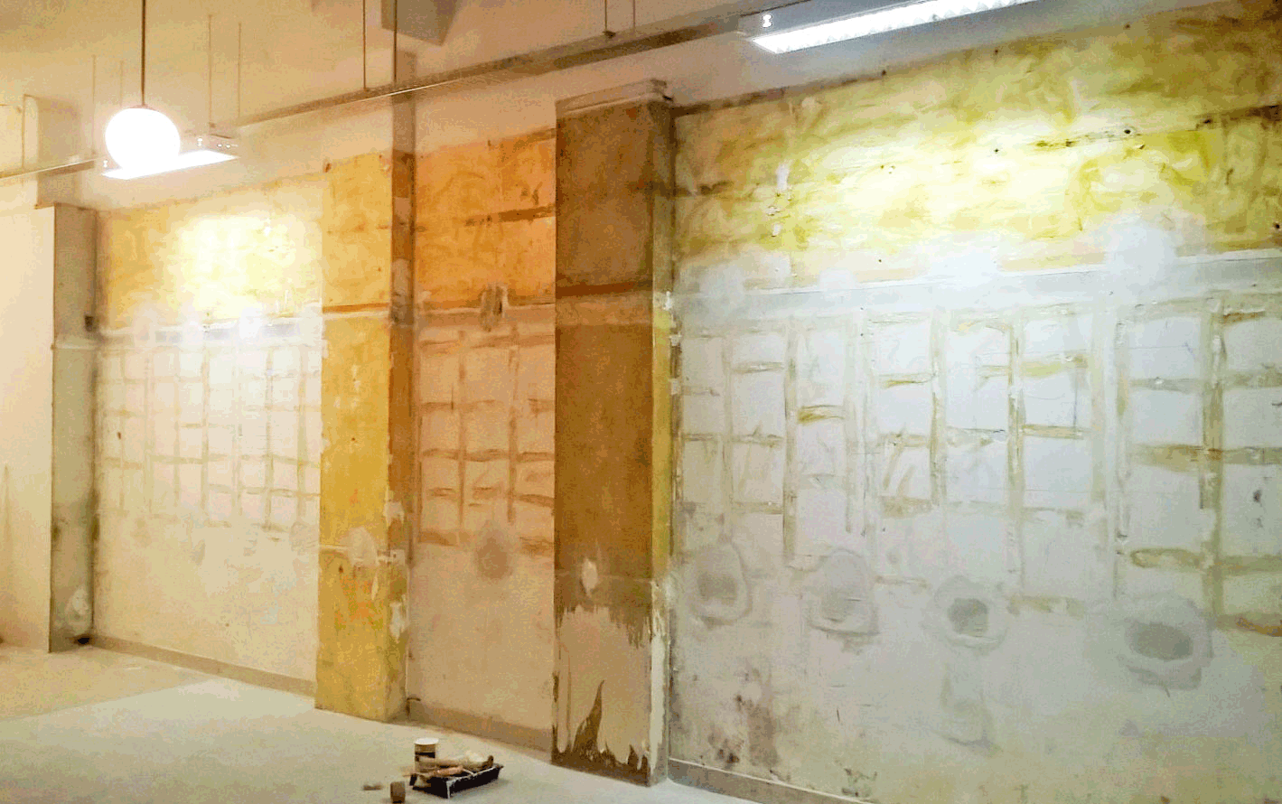 We had this big naked wall with approximately 7m width and 3m height with all the remains still stuck to it after the first construction in our collective studio in Lisbon. The first idea was simply to recover the look and paint it all in white, and then think about how to decorate and intervene on it. Then with a closer look, we realized the wall had several original records written in pencil that combined with the stone and glue, not only should be preserved but highlighted because it´s an original memory of the wall built over 30 years ago. So we picked several canvas, studied the best position and painted all in white except the canvas areas. The result is the transformation of an ordinary and "noisy" wall into an original artwork.