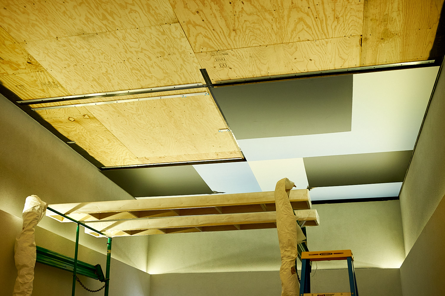 Construction site with wooden panels on ceiling and scaffolding.