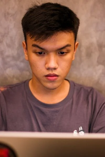 Serious looking male asian student looking at his laptop