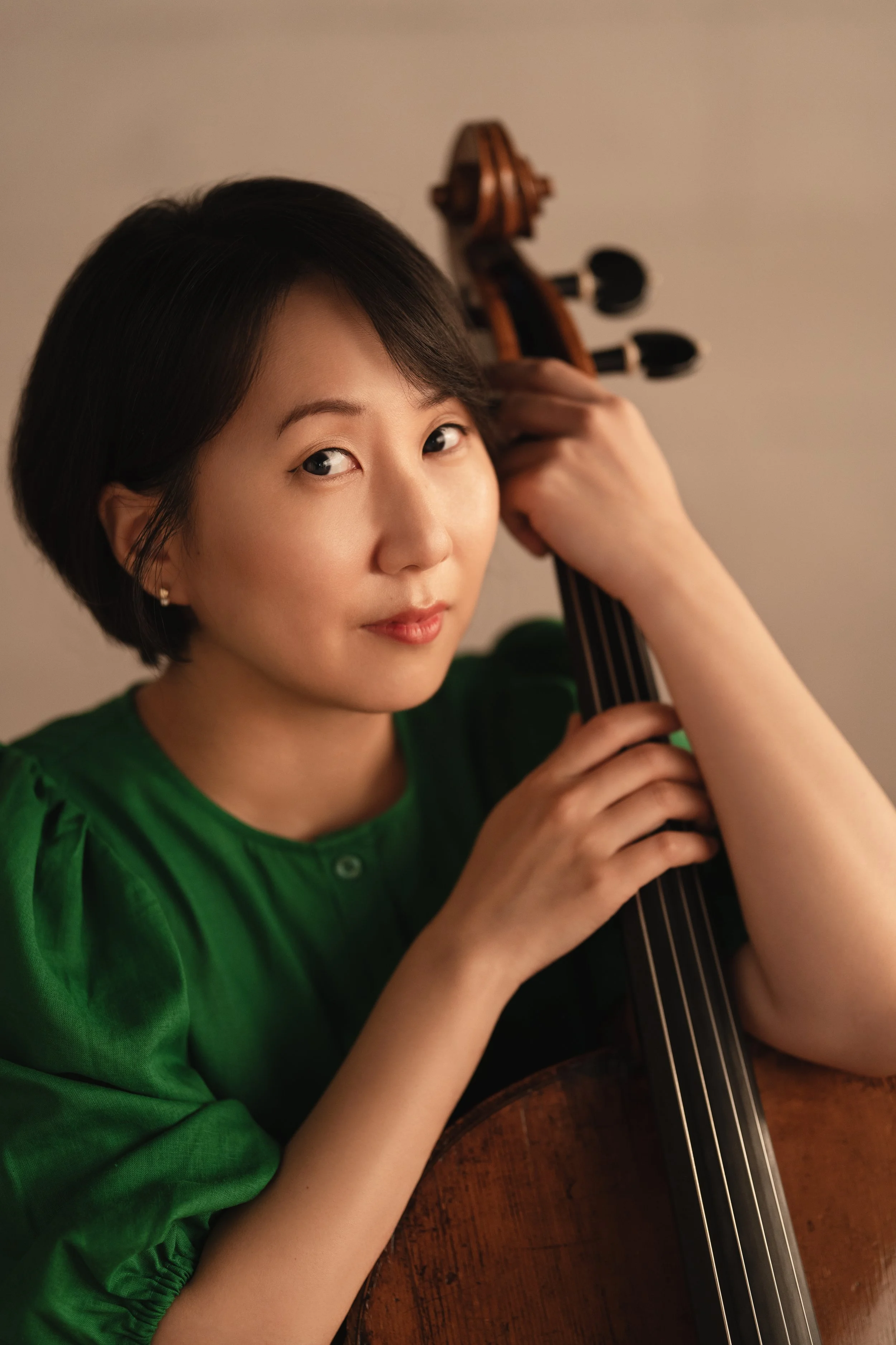 Professional cellist Julia Kang holding her cello in a portrait session.