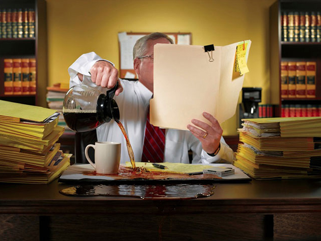 Image of man over pouring coffee onto his desk. 