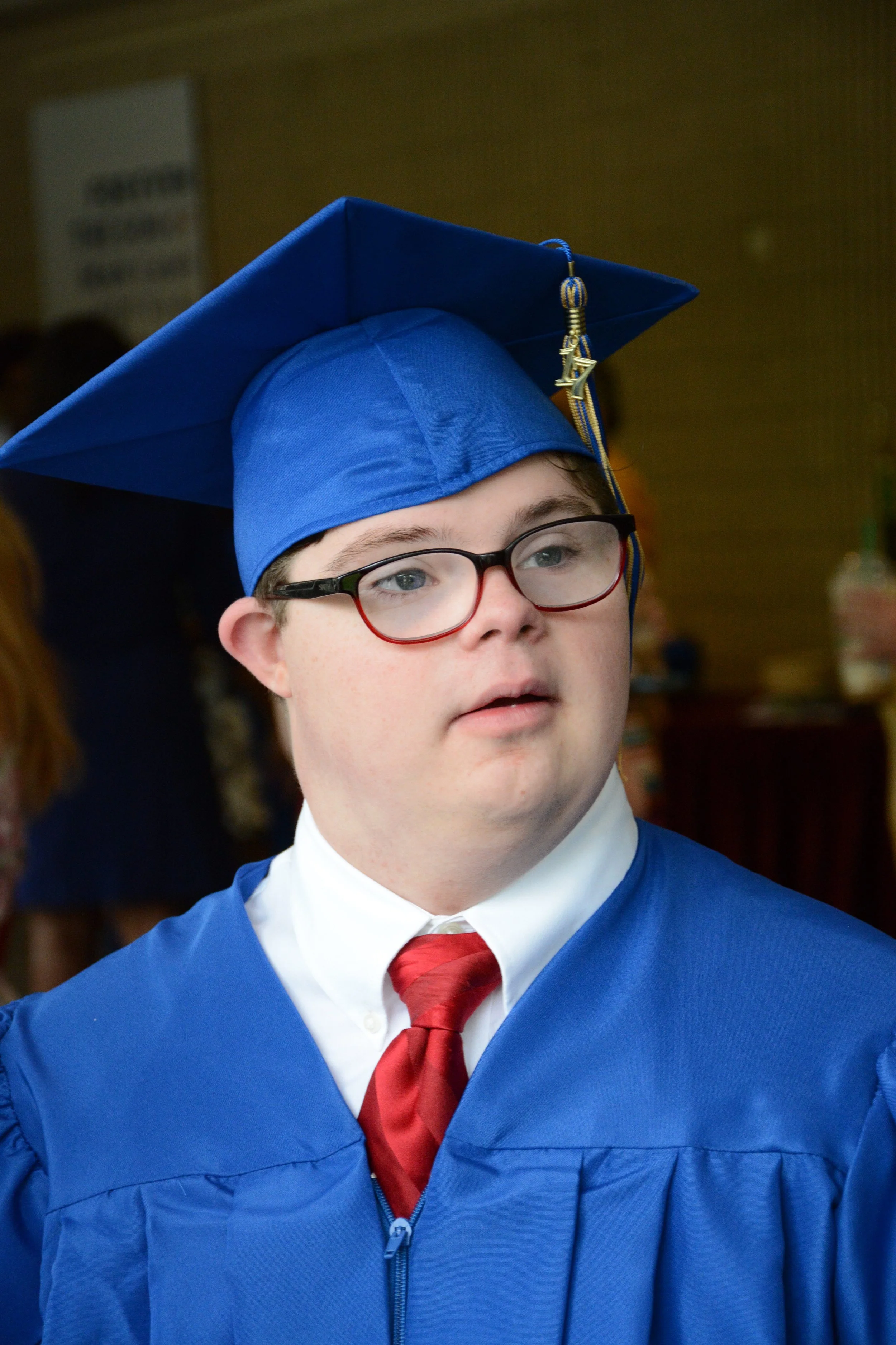 Image of a young man with down syndrome in his graduation cap and gown.