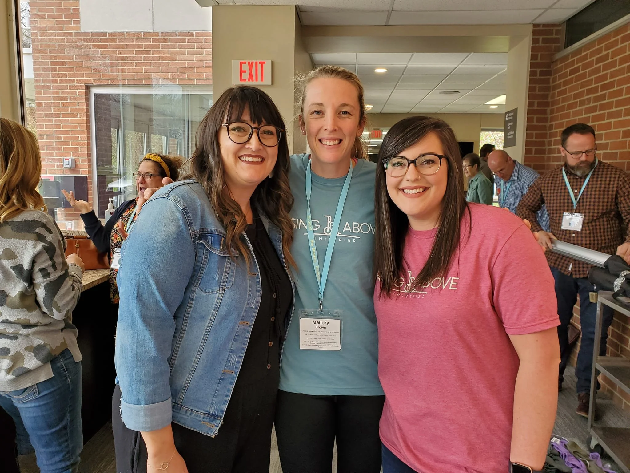 Image of women from the 2022 conference.  Two are wearing Rising Above Ministries shirts