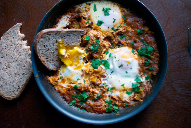 Ingredients 1 tbsp. extra-virgin olive oil 1/2 yellow onion, finely chopped 1 large garlic clove, minced 1/2 bell pepper (red or yellow), diced 1/2 tsp. paprika 1/4 tsp. cumin pinch of cayenne 1 cup fresh spinach 1 14 oz. can whole plum tomatoes 3 large eggs 1 handful fresh parsley leaves and tender stems a few leaves fresh basil or 1 tbsp. dried basil salt and freshly ground black pepper, to taste Heat the oil in a medium-sized skillet over medium heat. Add the onion and garlic, stirring occasionally, being careful not to let it burn. When it's soft and golden brown, add the bell pepper, paprika, cumin, and cayenne and cook for another couple of minutes. While the veggies are cooking, place the spinach and tomatoes in a food processor or blender and mix until it is the consistency of a finely chopped tomato sauce. Pour the sauce into the skillet and let cook, covered, for 15-25 minutes, or until thickened slightly. As it cooks, the mixture should be heavily simmering, but not boiling. Taste the sauce—if you want more of a kick, add more cayenne. Using a wooden spoon, make three small divots in the sauce and carefully crack the eggs into them. Cover the skillet with a lid and cook for 5 more minutes or until the egg whites have set. Don't walk away— as soon as the egg whites are set, remove the pan from the heat. It is easy to overcook the eggs, and you want the yolk to remain runny. Sprinkle the pan with fresh basil, parsley, and salt and black pepper to taste. Serve with multigrain bread or fresh pita. Enjoy! Recipe adapted from Green Kitchen Stories