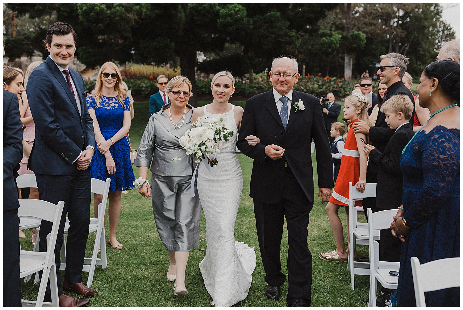 Bride walks down the aisle with her parents in the Royal Botanic Gardens