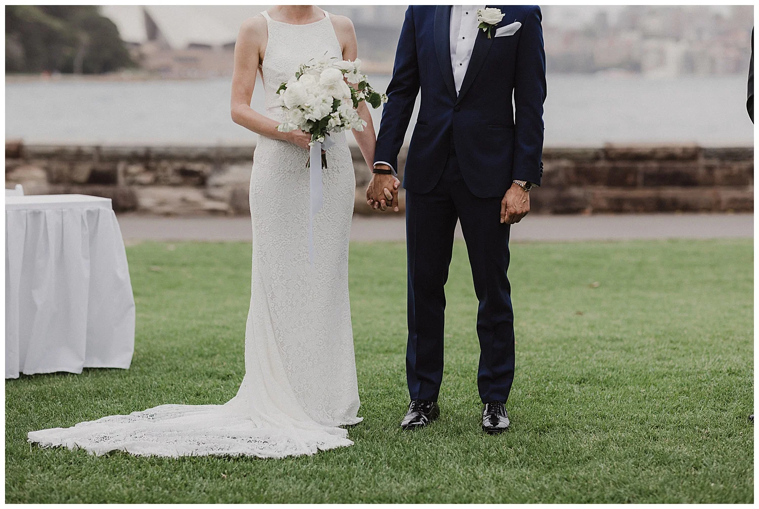 Couple holds hands during wedding. Dress by Karen Willis Holmes, Flowers by Poho, tux by The Bespoke Corner Tailor
