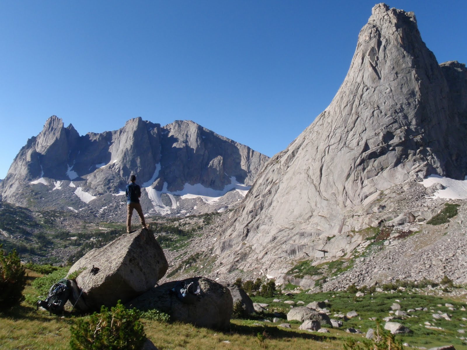 Day 8 A standing on large boulder view towards Warbonnet The Warriors and Pingora from high plateau below Texas Pass.JPG