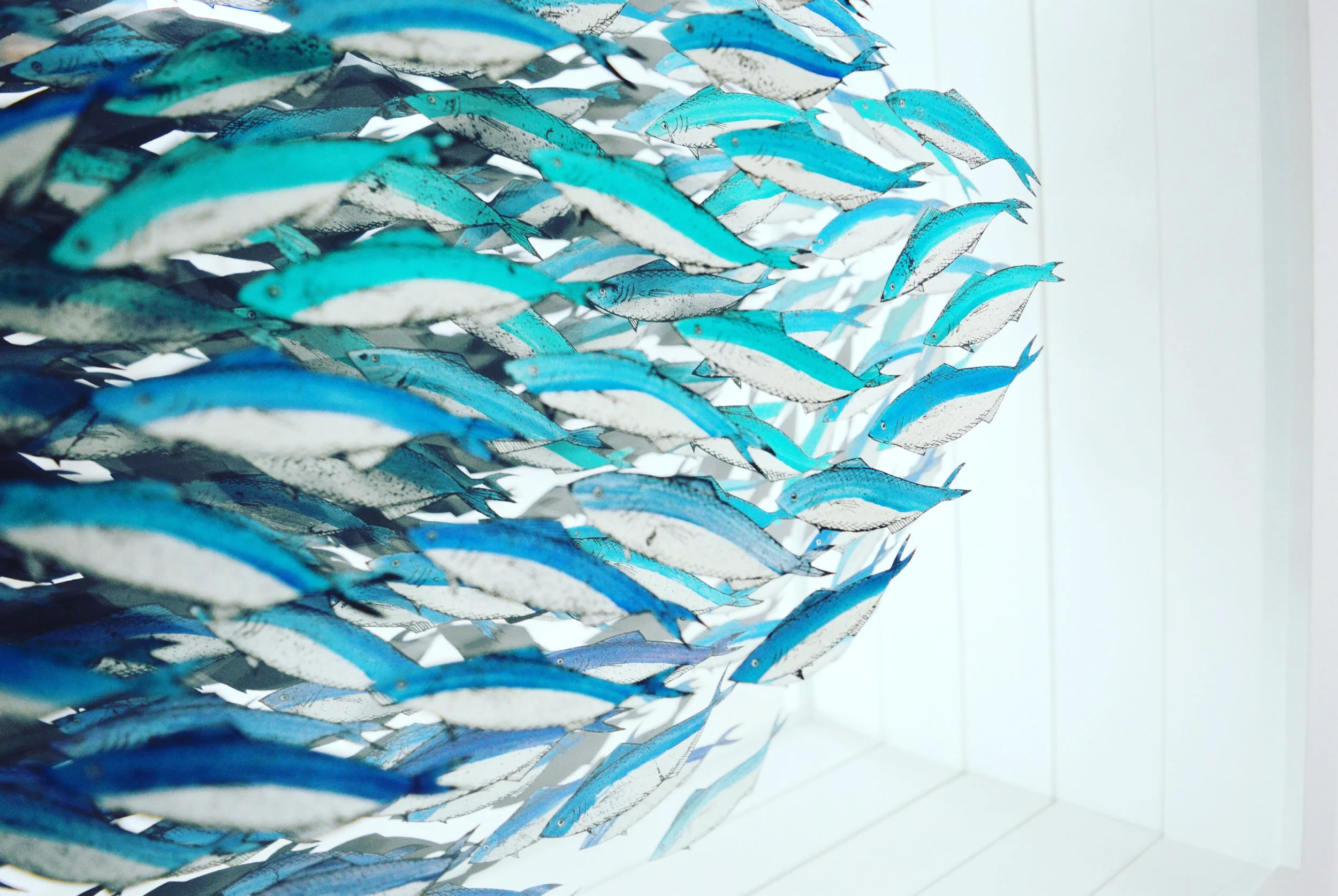 Verre-églomisé artwork depicting a swirling shoal of blue and white fish