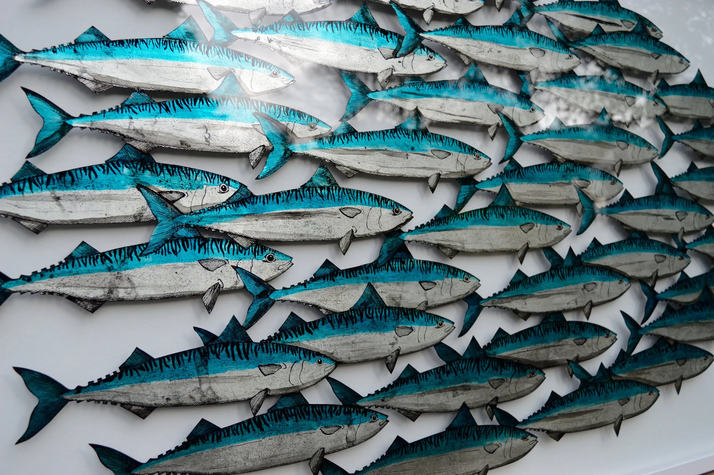 Close-up of a Verre-églomisé artwork depicting a shoal of blue and silver fish