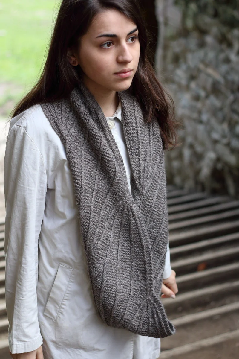 Winterlong Scarf by Bristol Ivy A garter and tuck stitch cowl that uses increases and decreases to open and close a series of geometric, organic shapes: diamonds, buds, or blossoms. Winterlong is started from a provisional cast on, and worked flat to the knitter’s desired length. Skills needed: increasing, decreasing, provisional cast on, 3 needle bind off. Yarn: Baa Ram Ewe's Dovestone Natural Aran (170m in 100g) Yarn Quantities: 400 - 425 yards (366 - 389 m) Needles: 5mm straights (or 40cm circular) Size: 59” circumference, 7 1/4” depth