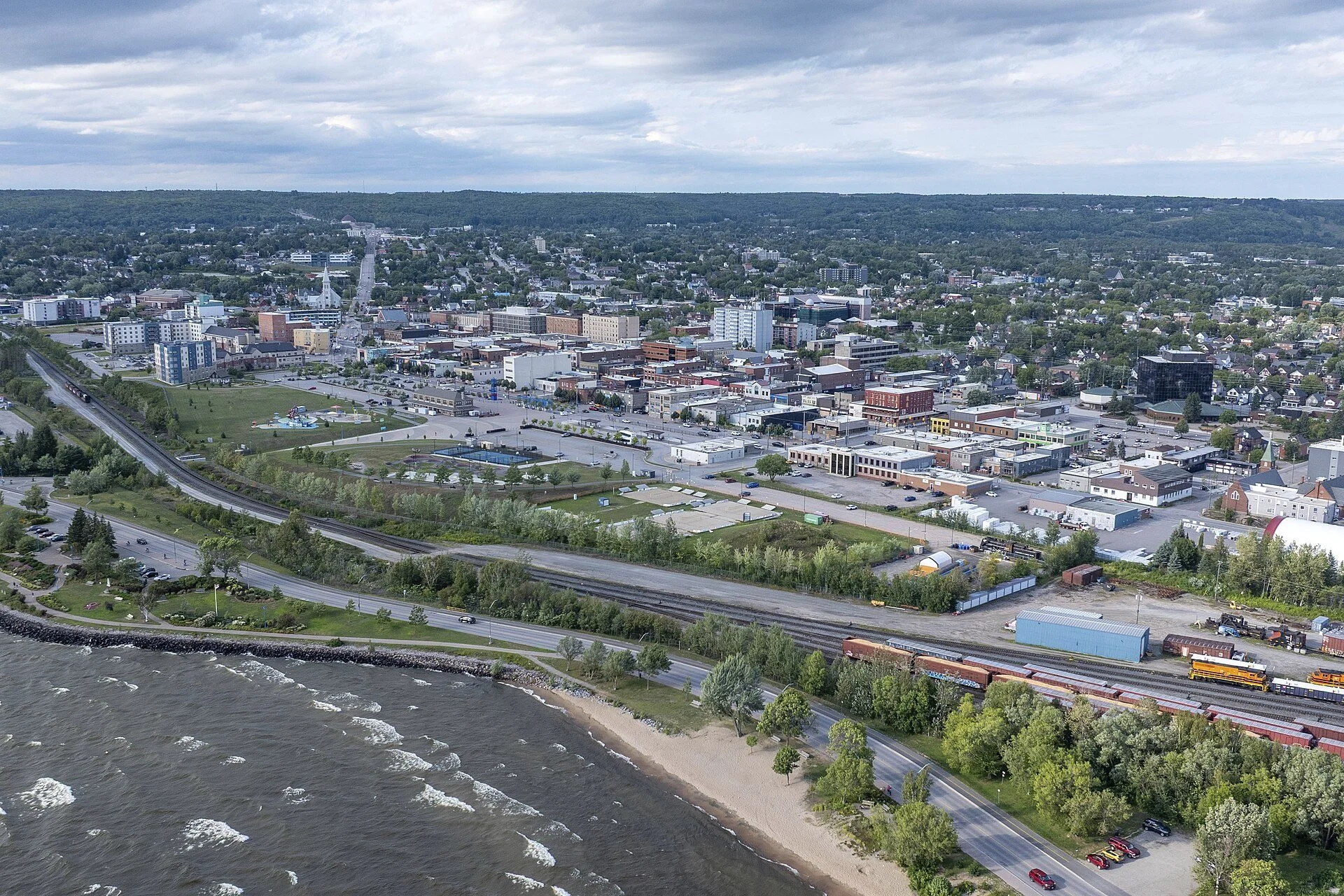 An aerial view of North Bay with the Lake Nipissing shoreline and beach in the foreground and the city beyond.