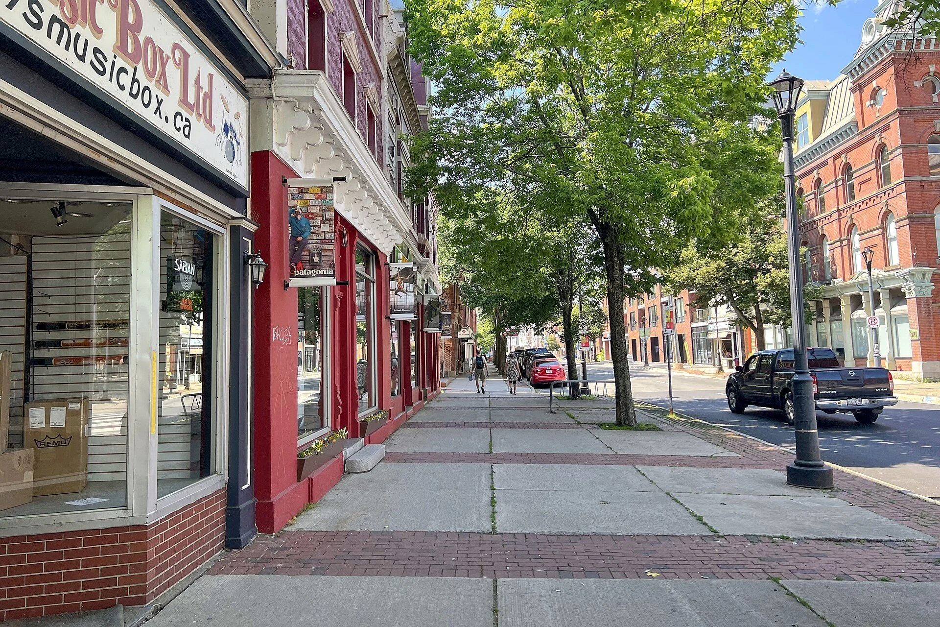 Brick storefronts and a tree-lined sidewalk on Queen Street in downtown Fredericton.